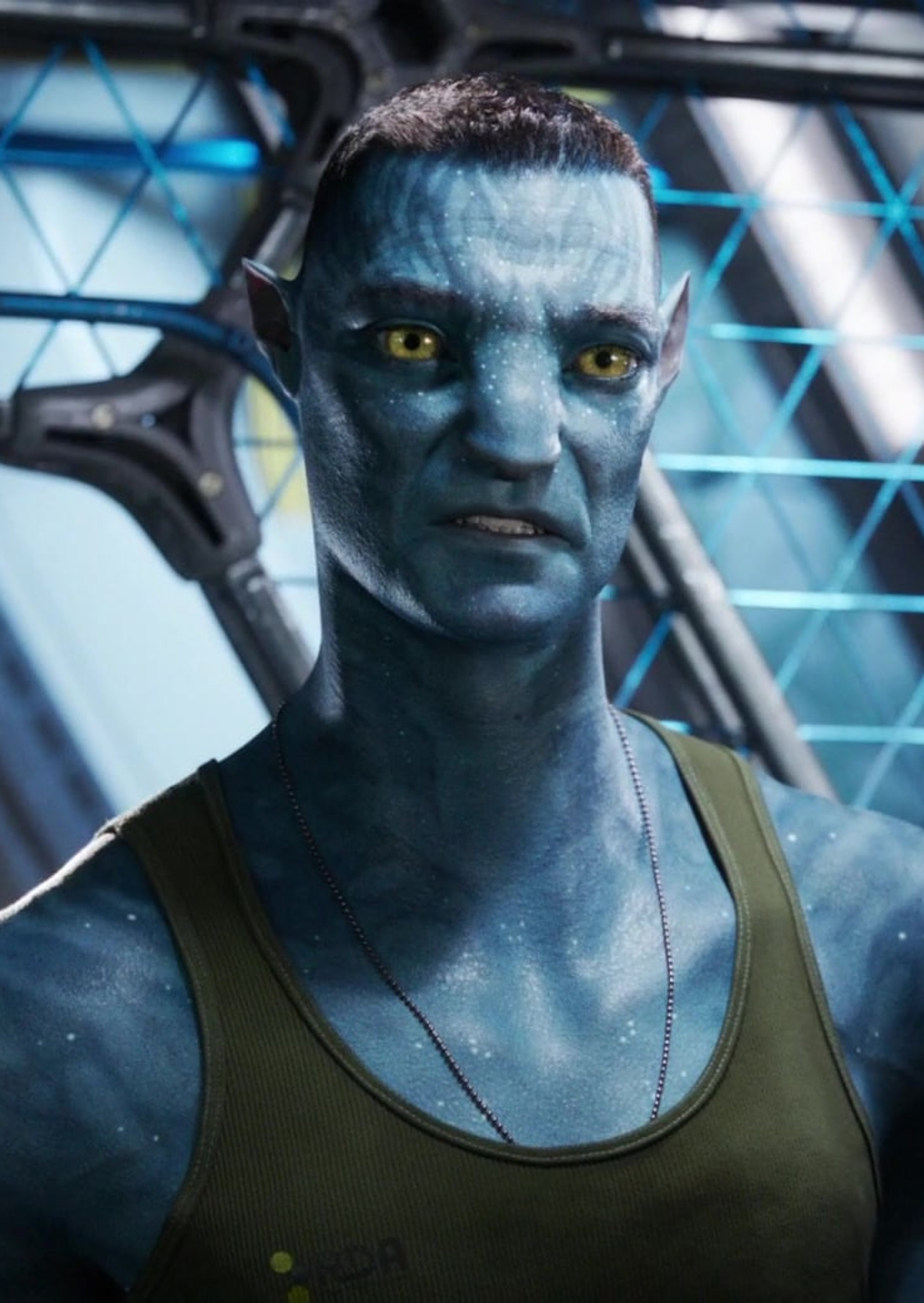 A blue-skinned humanoid character with glowing yellow eyes and a muscular build, wearing a green tank top in a military or industrial setting.