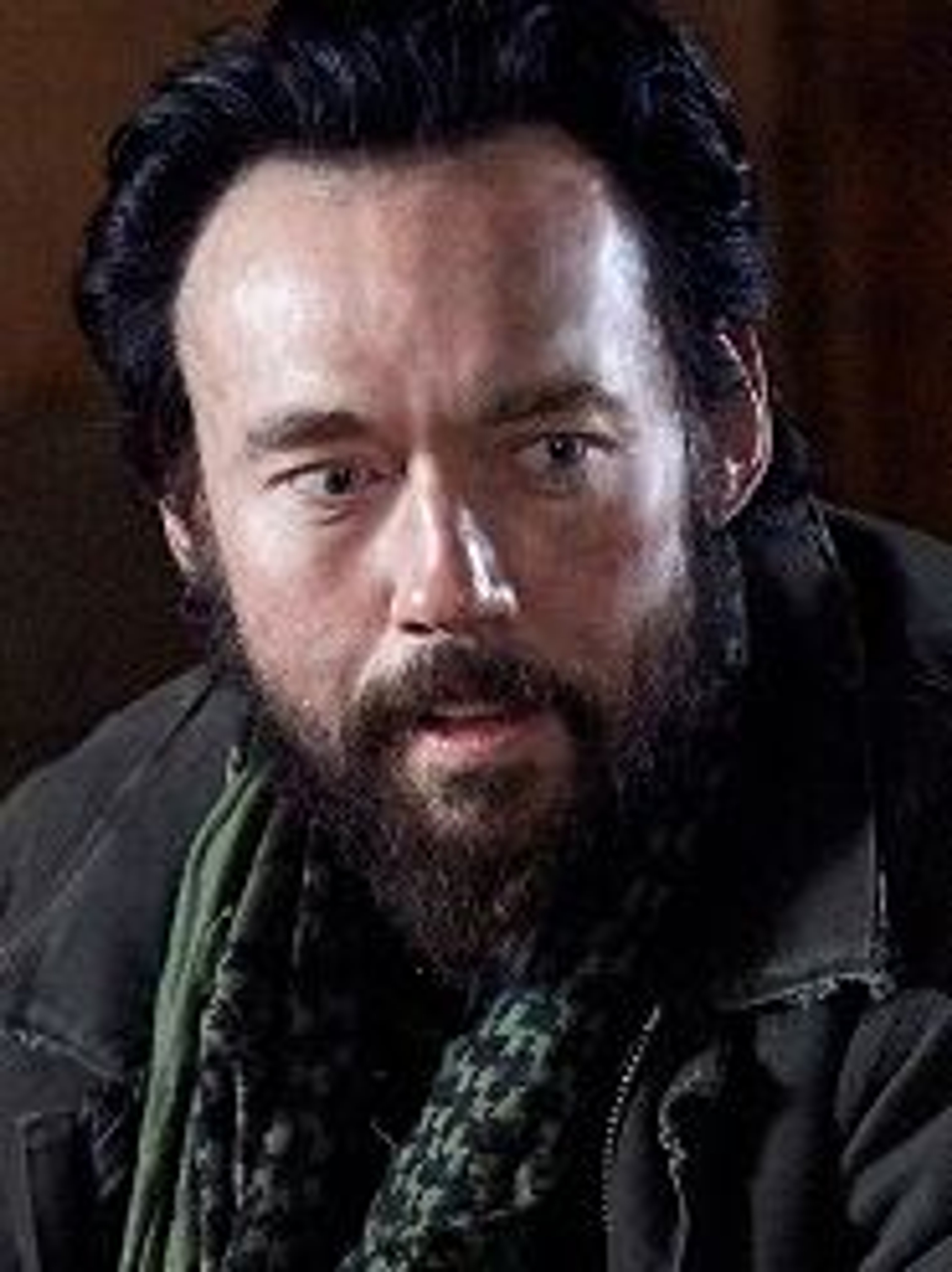 A middle-aged man with a thick beard and intense expression