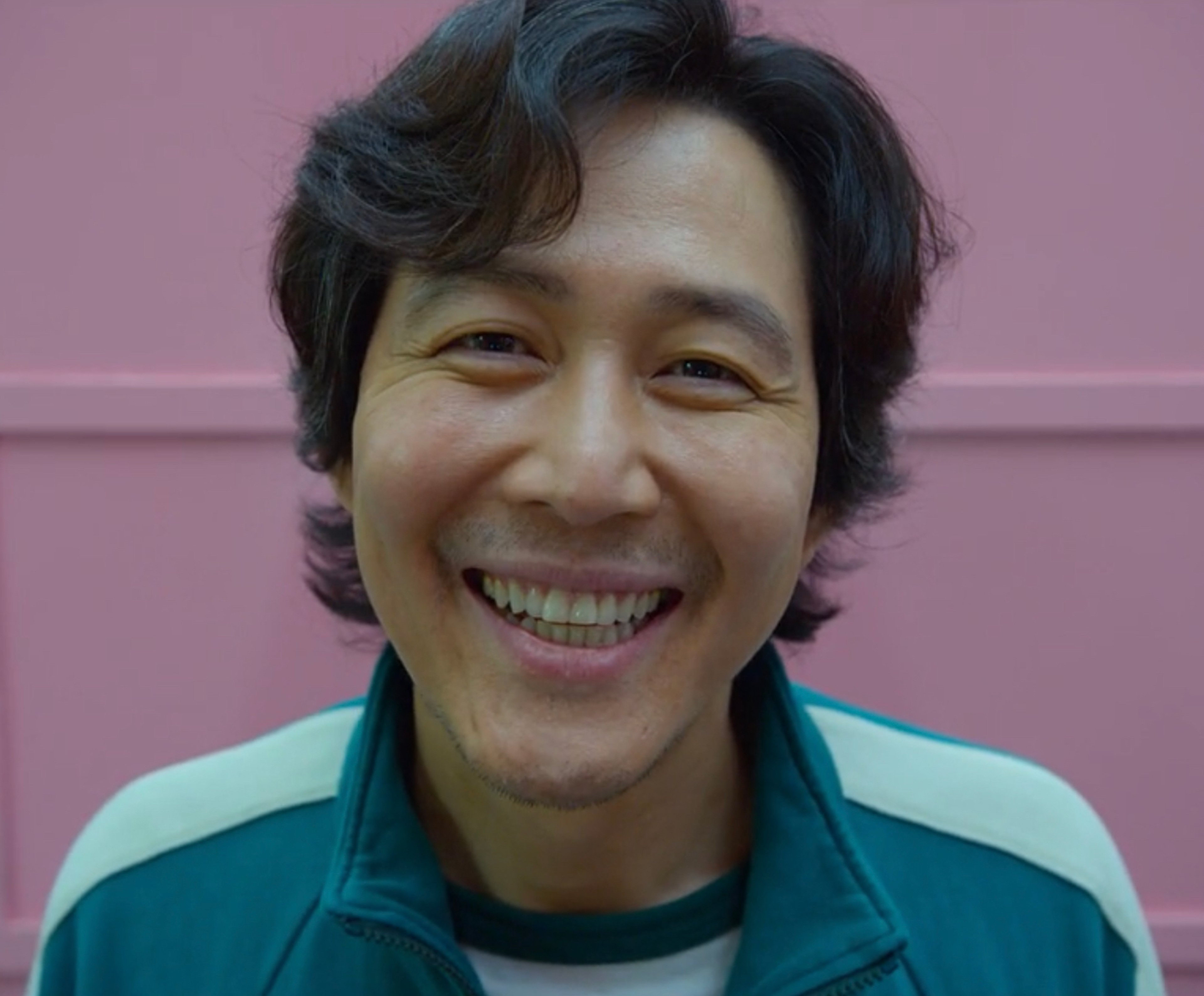 A smiling middle-aged Asian man in a green jacket