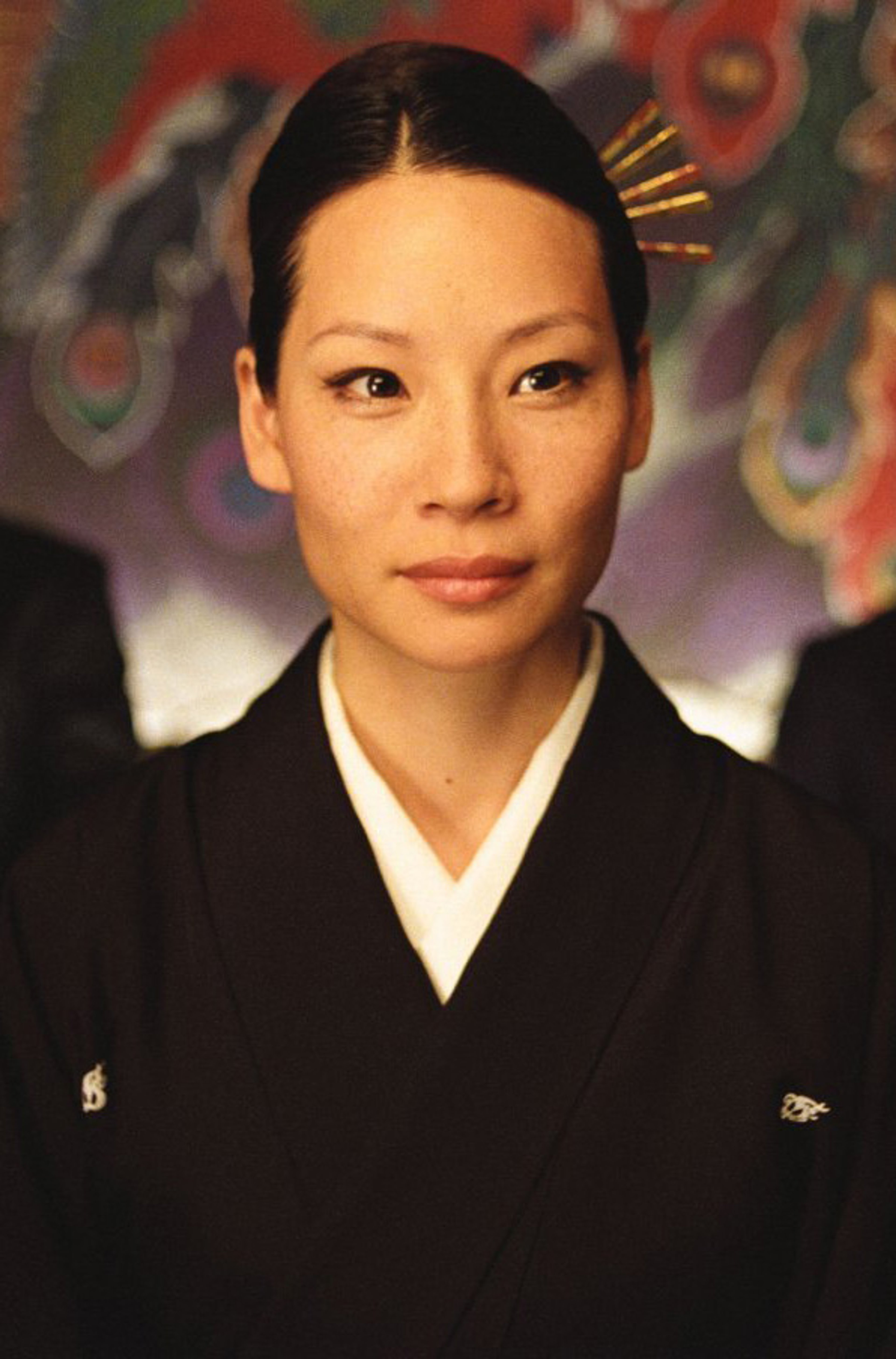 A woman with dark hair wearing a black kimono-style outfit, looking serious and focused.