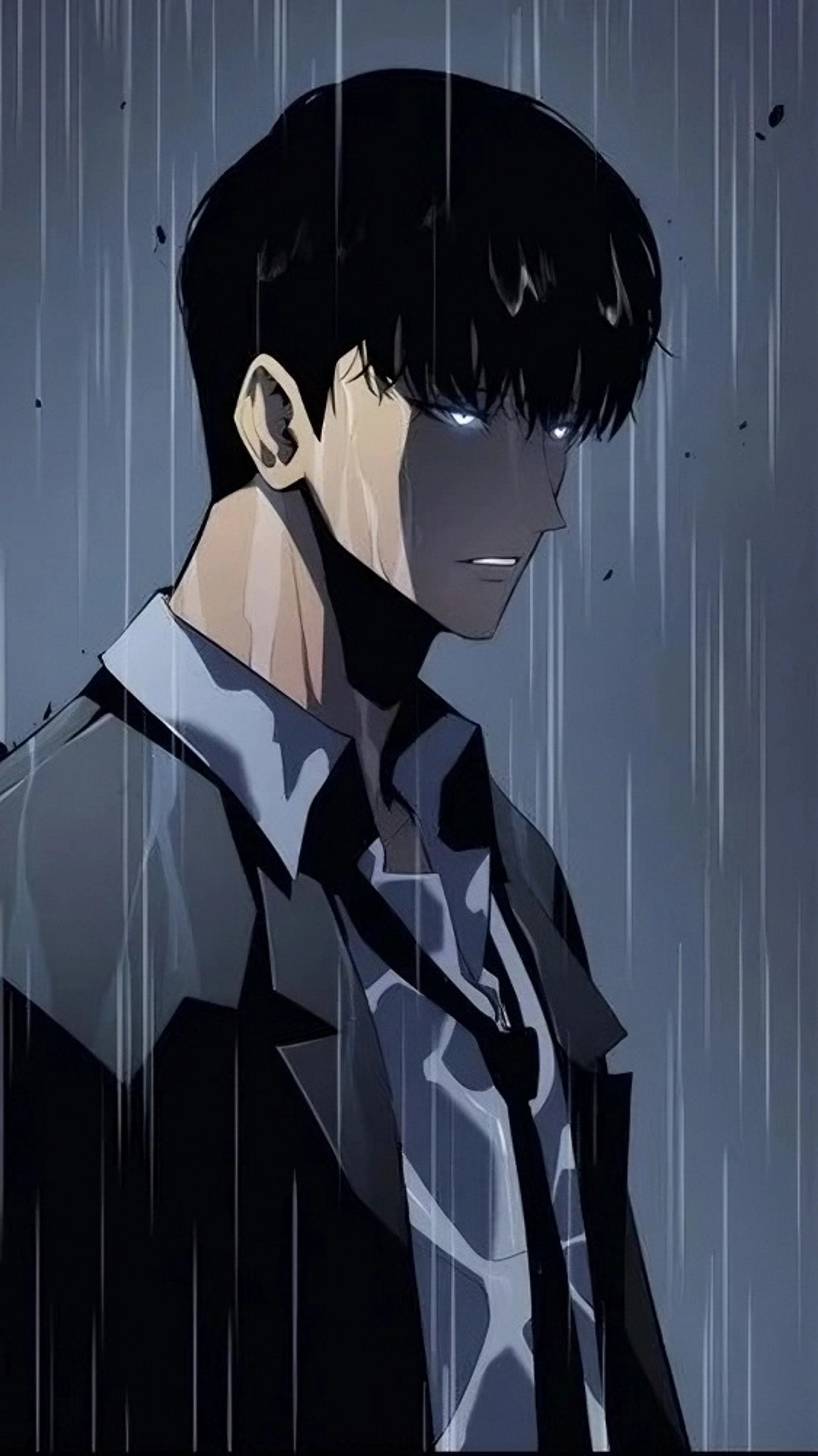 A young man with dark hair wearing a black coat, standing in the rain