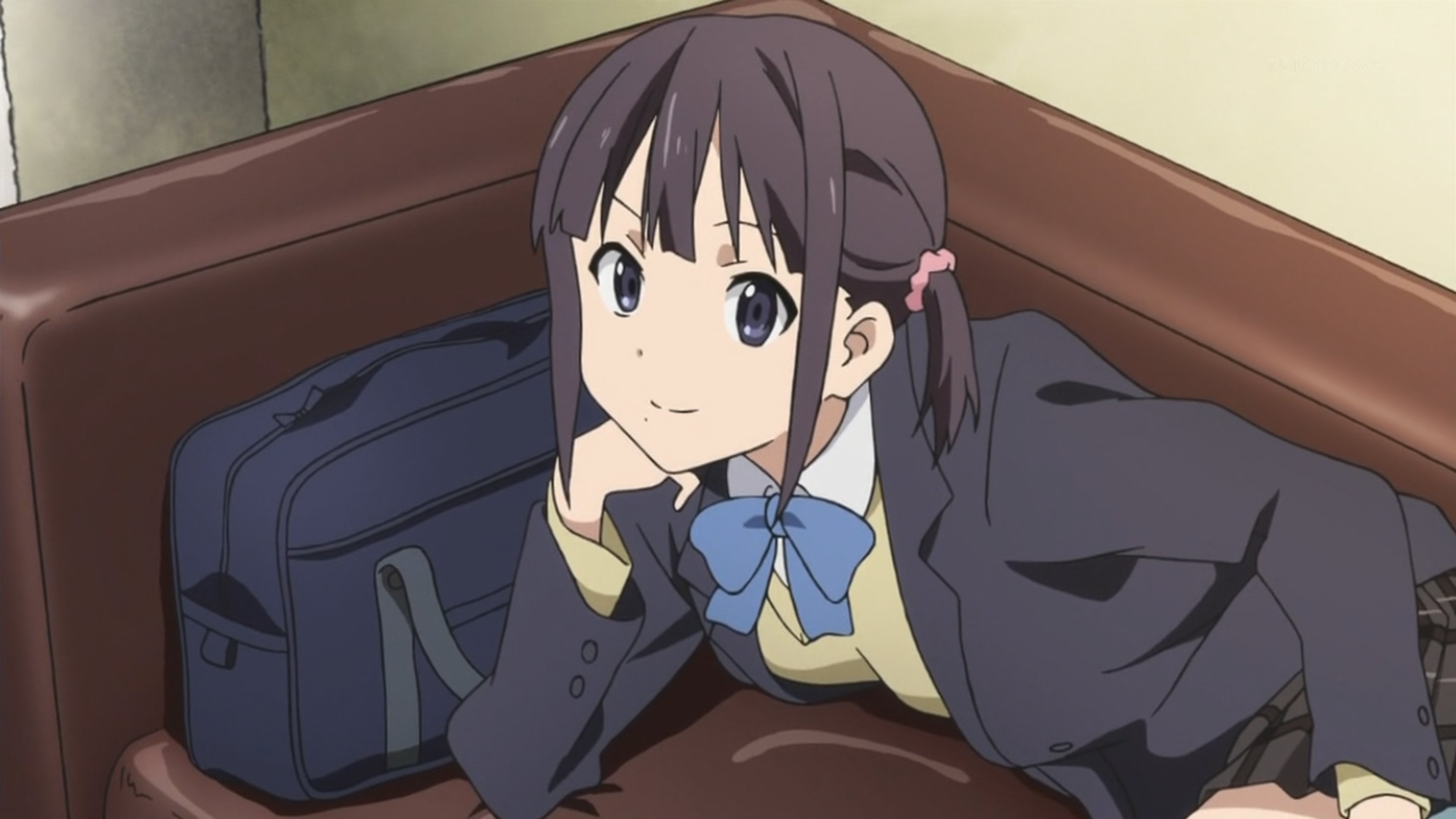 An anime-style character of a young female high school student with dark hair and blue eyes, wearing a school uniform and sitting on a couch or chair.
