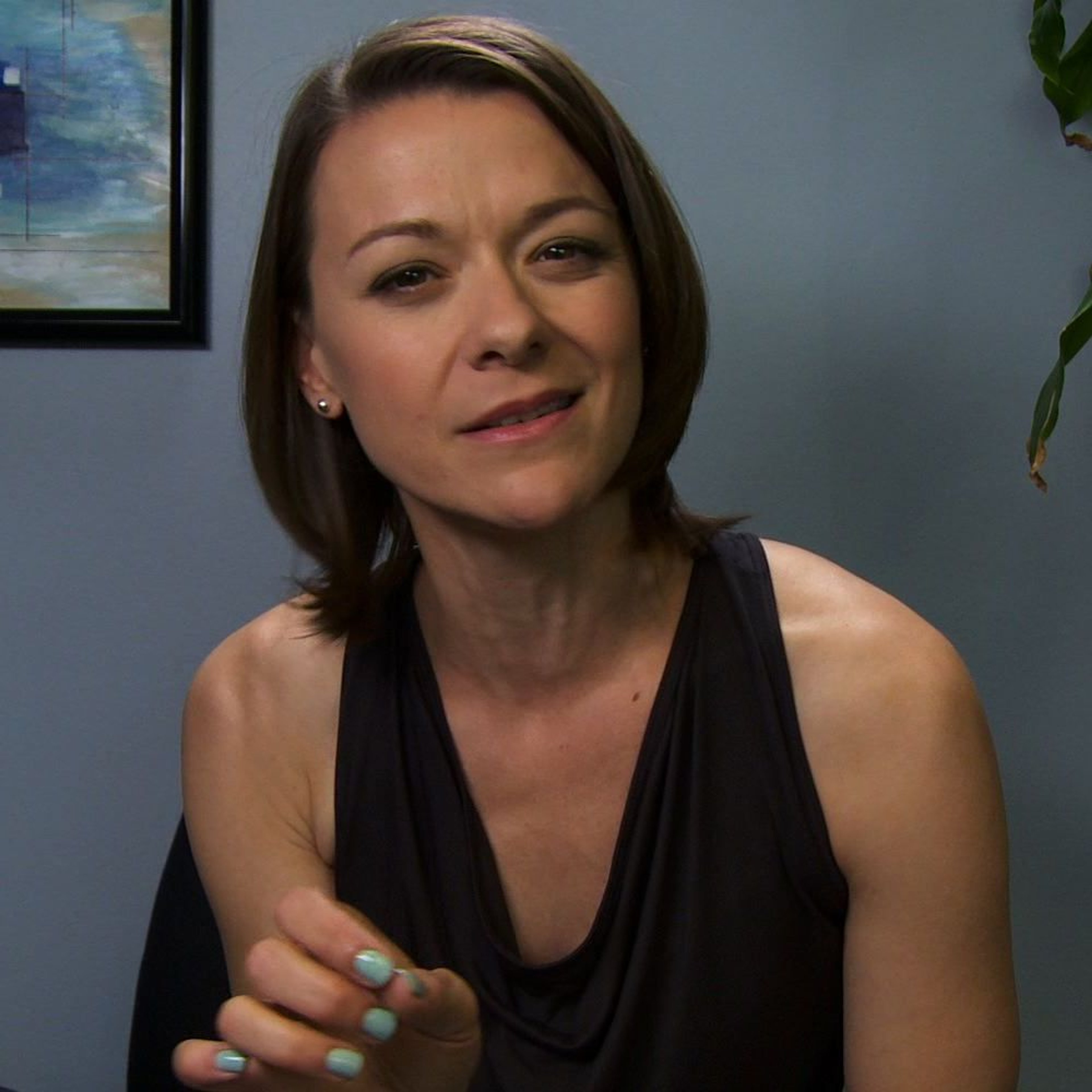 A middle-aged woman in a black dress with a serious expression