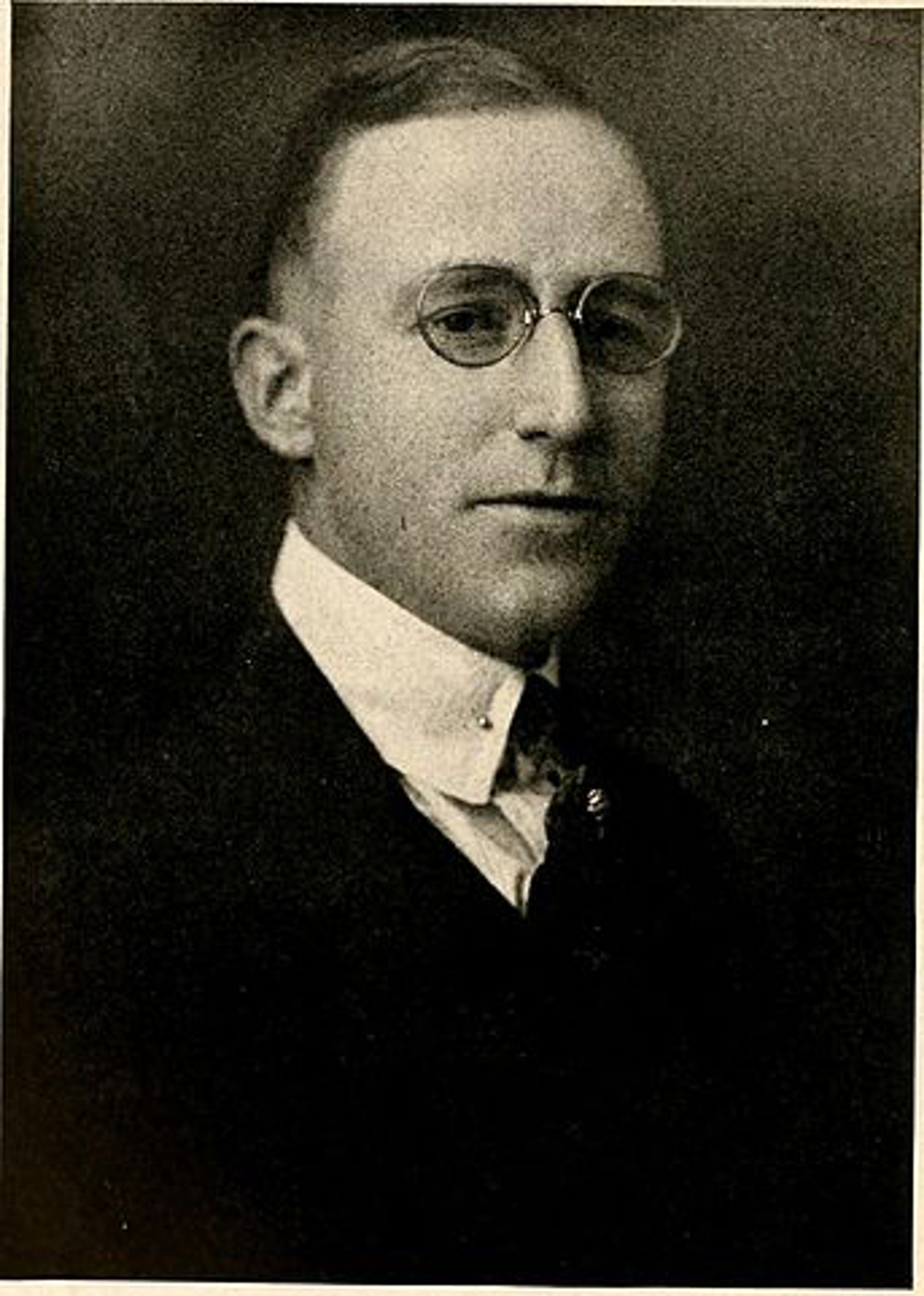 A middle-aged man in a suit and tie, with a serious expression