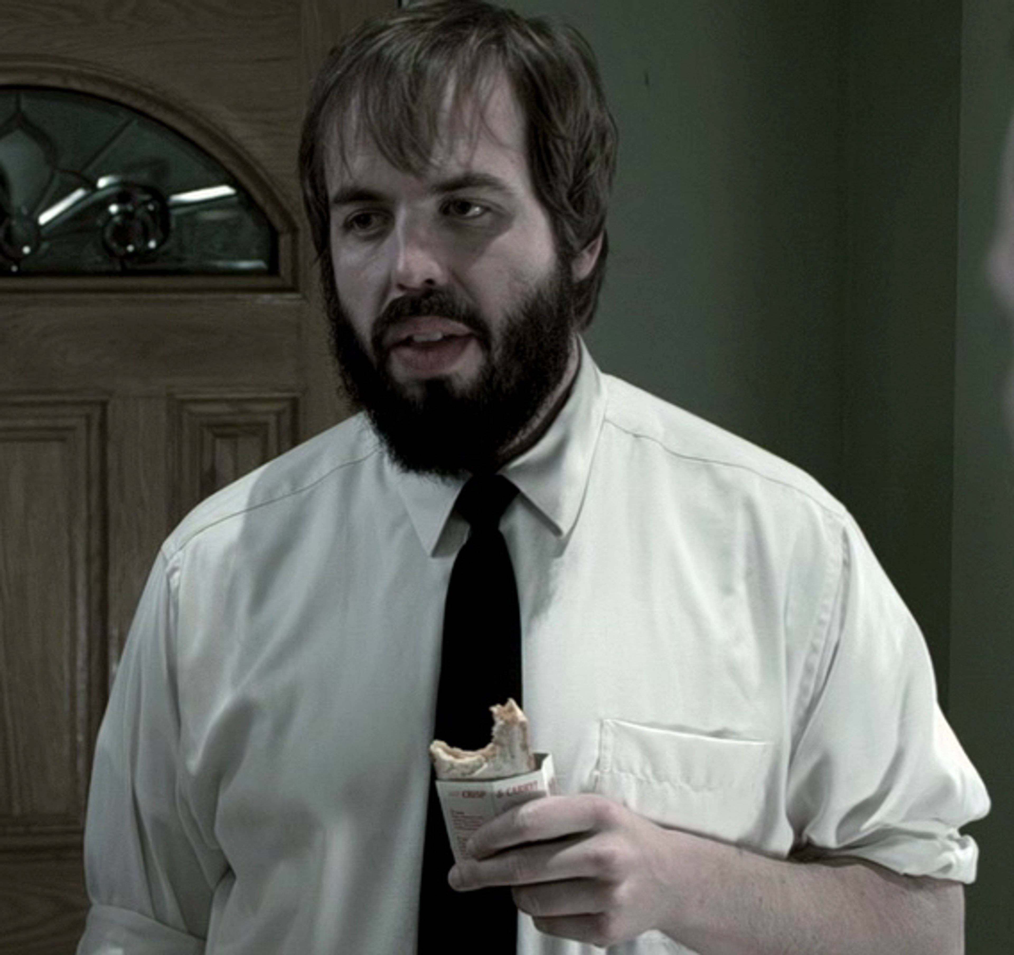 A middle-aged man with a beard and mustache, wearing a white shirt and tie, in a professional setting.