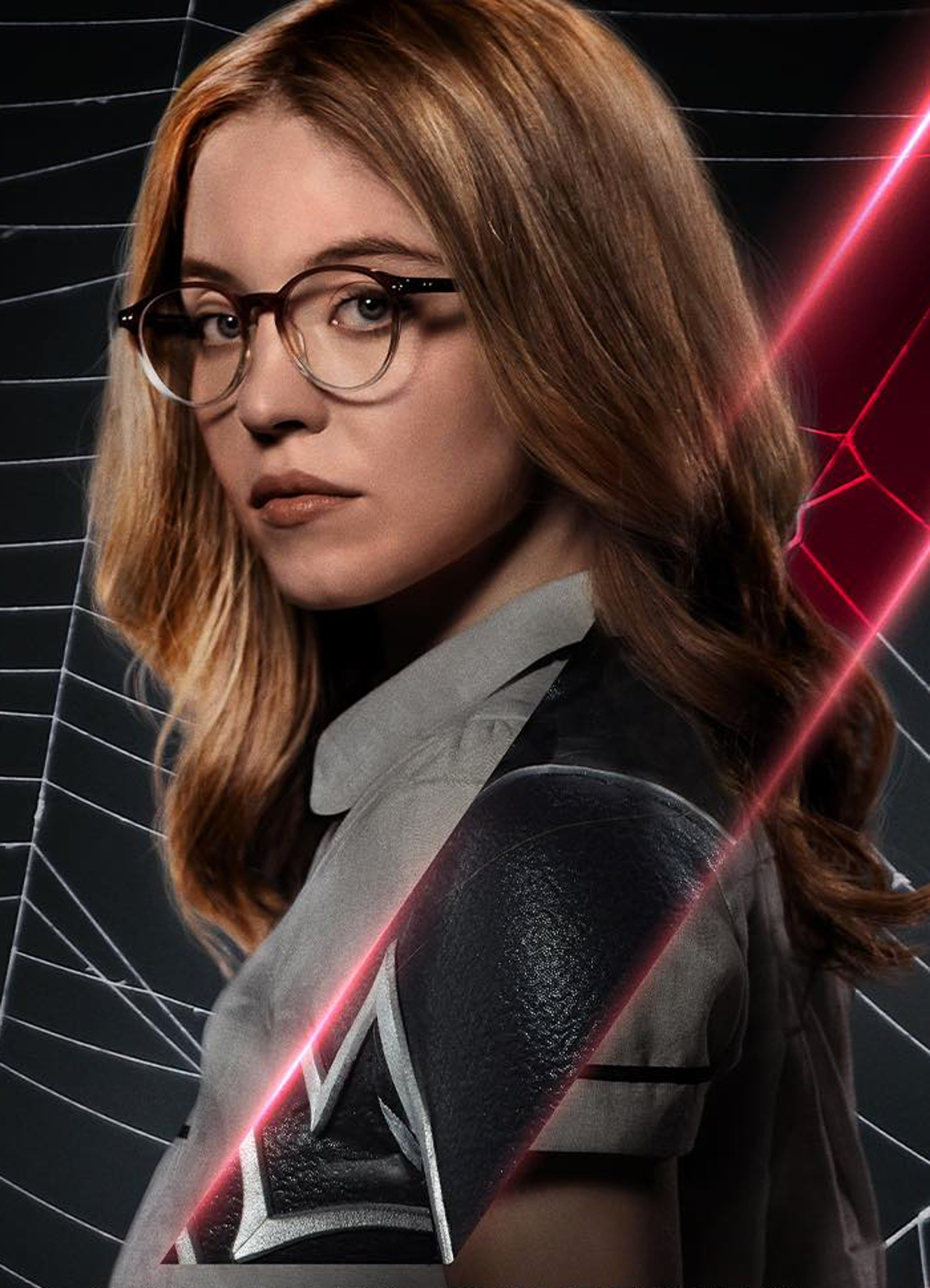 A woman with long brown hair wearing glasses and a black and gray outfit, standing in front of a dark background with red and black geometric shapes.