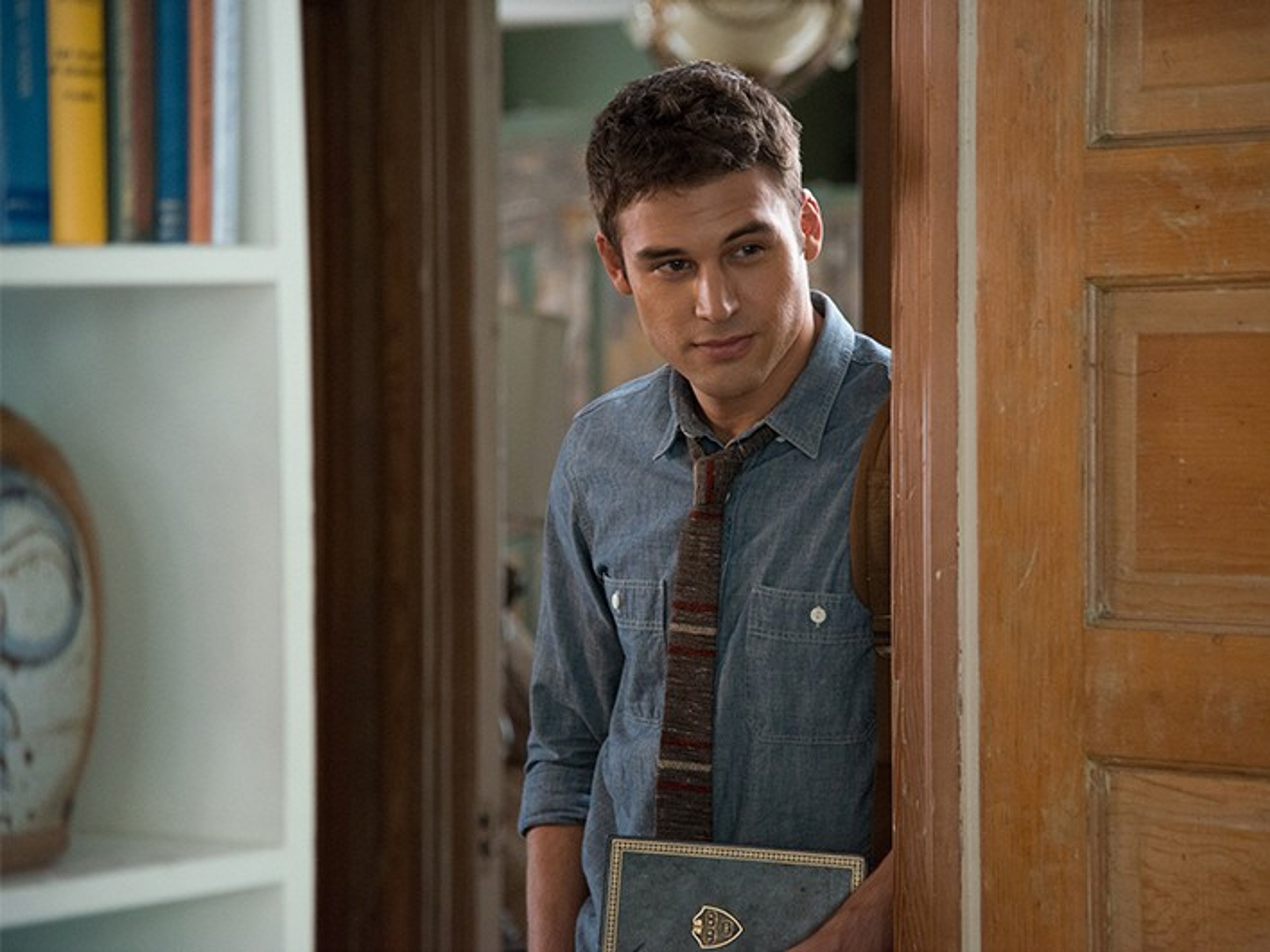 A young man with dark hair standing in a doorway