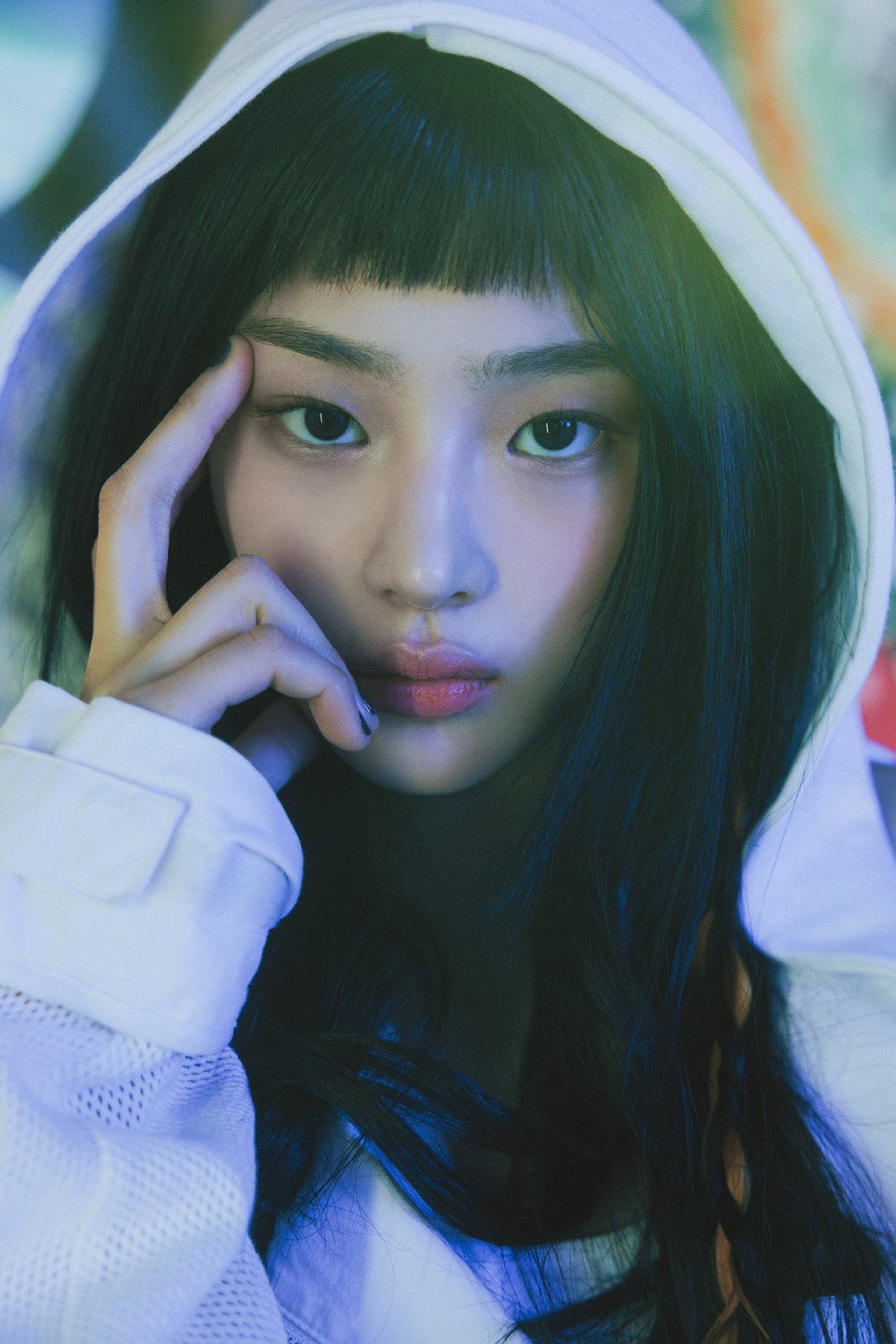 A young woman with long dark hair and a friendly expression, wearing a white hooded sweatshirt.