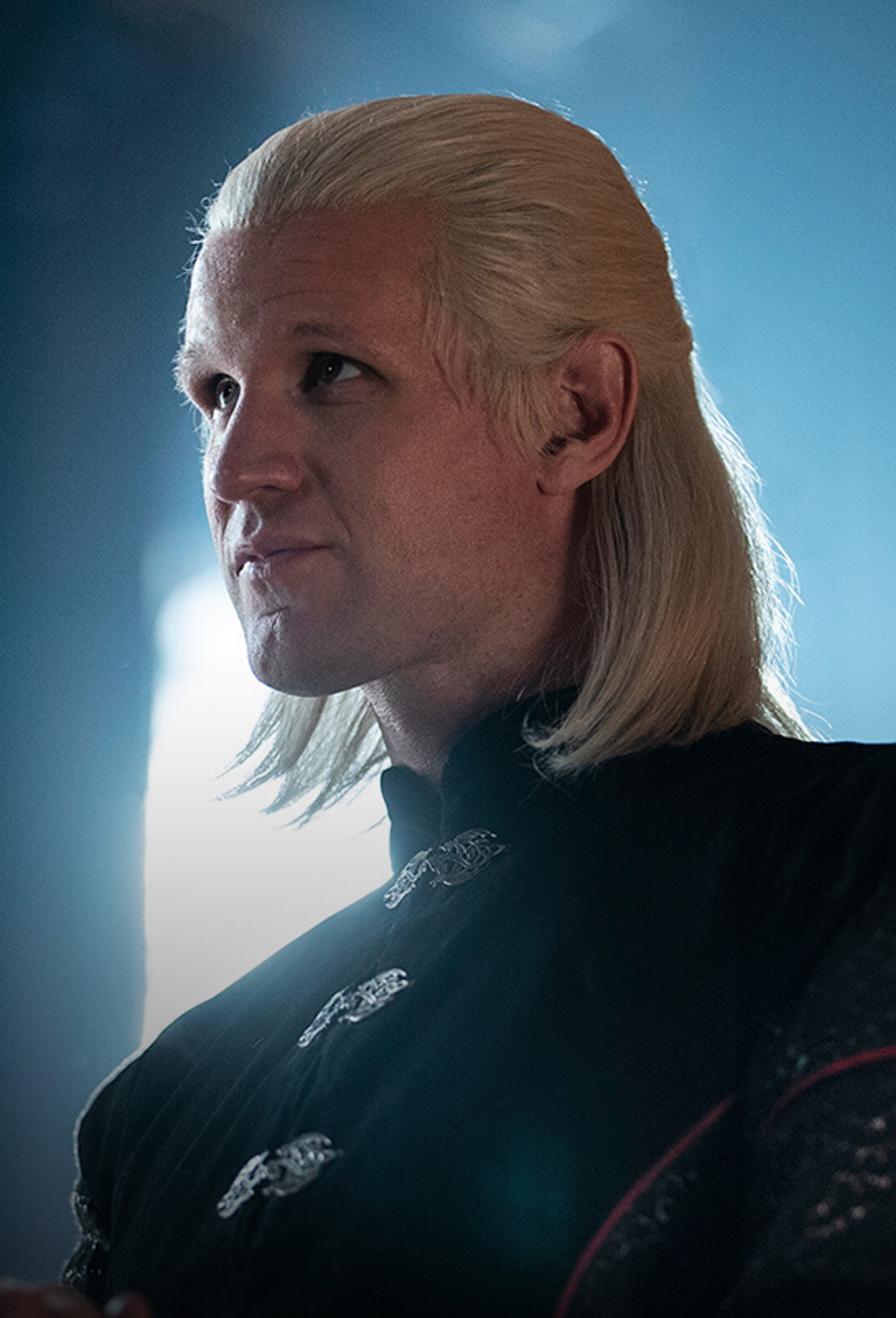 A portrait of a woman with silver-blonde hair and violet eyes, wearing a dark high-collared outfit.