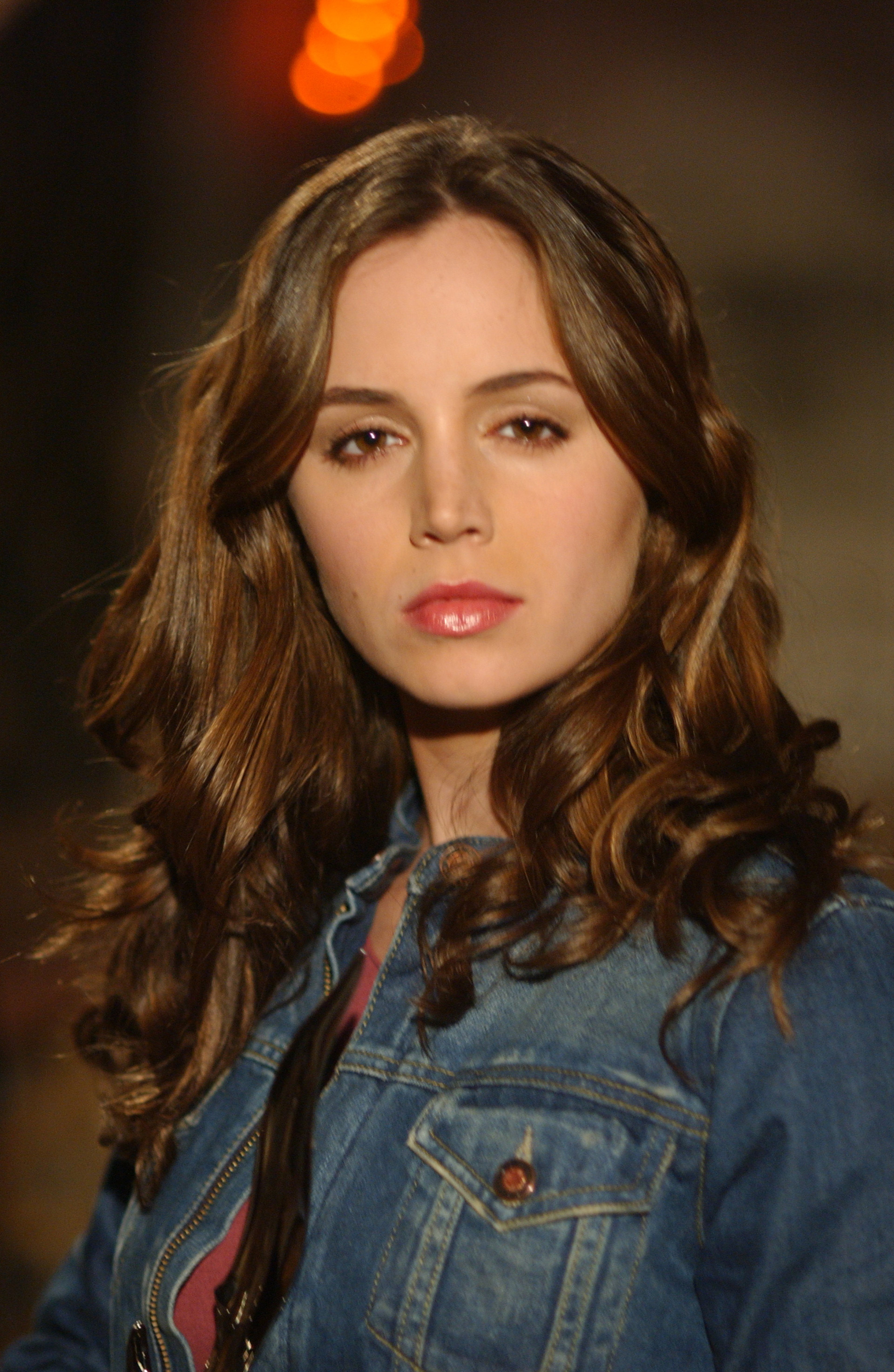 A young woman with long brown hair wearing a denim jacket
