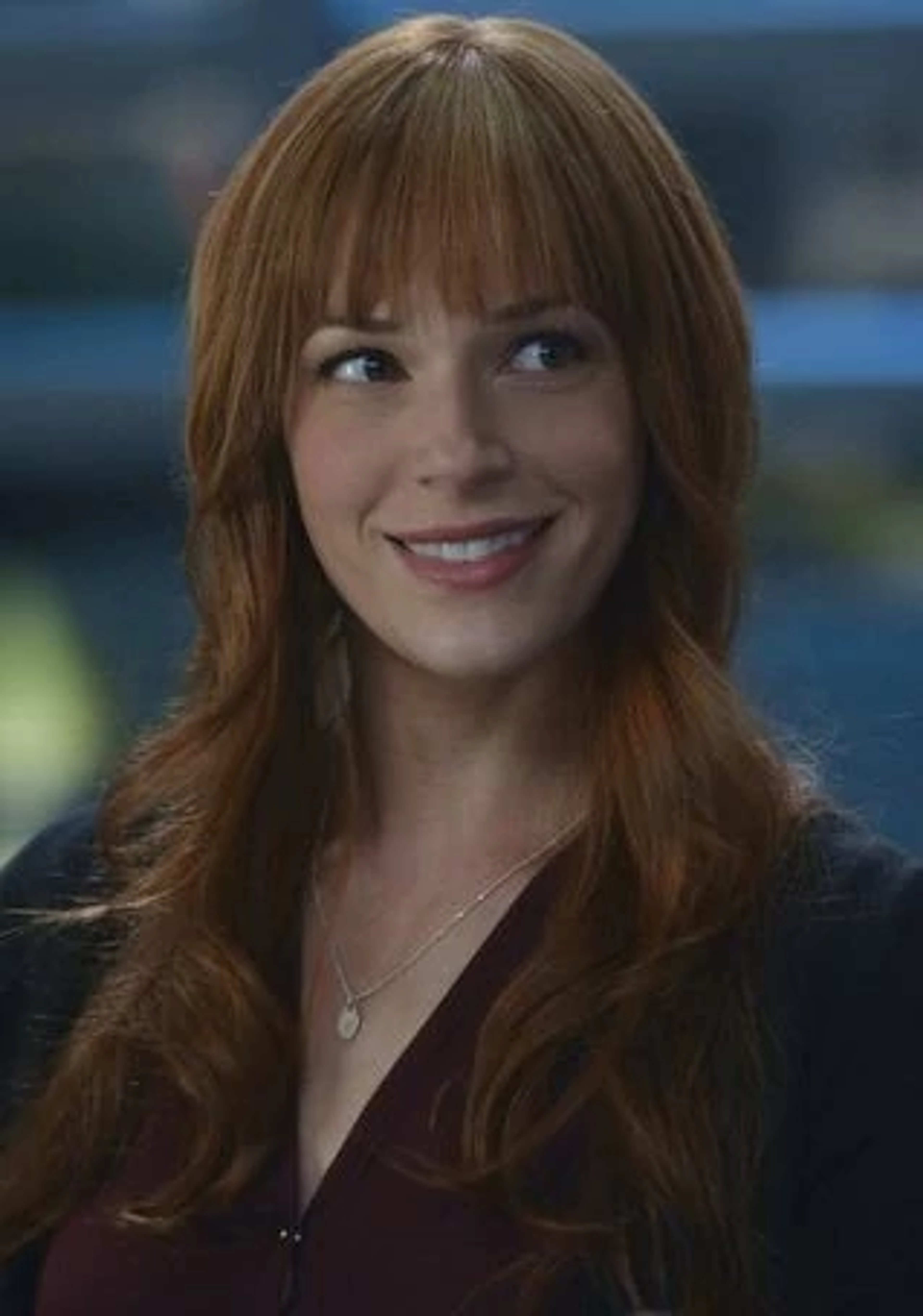 A woman with long, red hair and brown eyes smiling at the camera