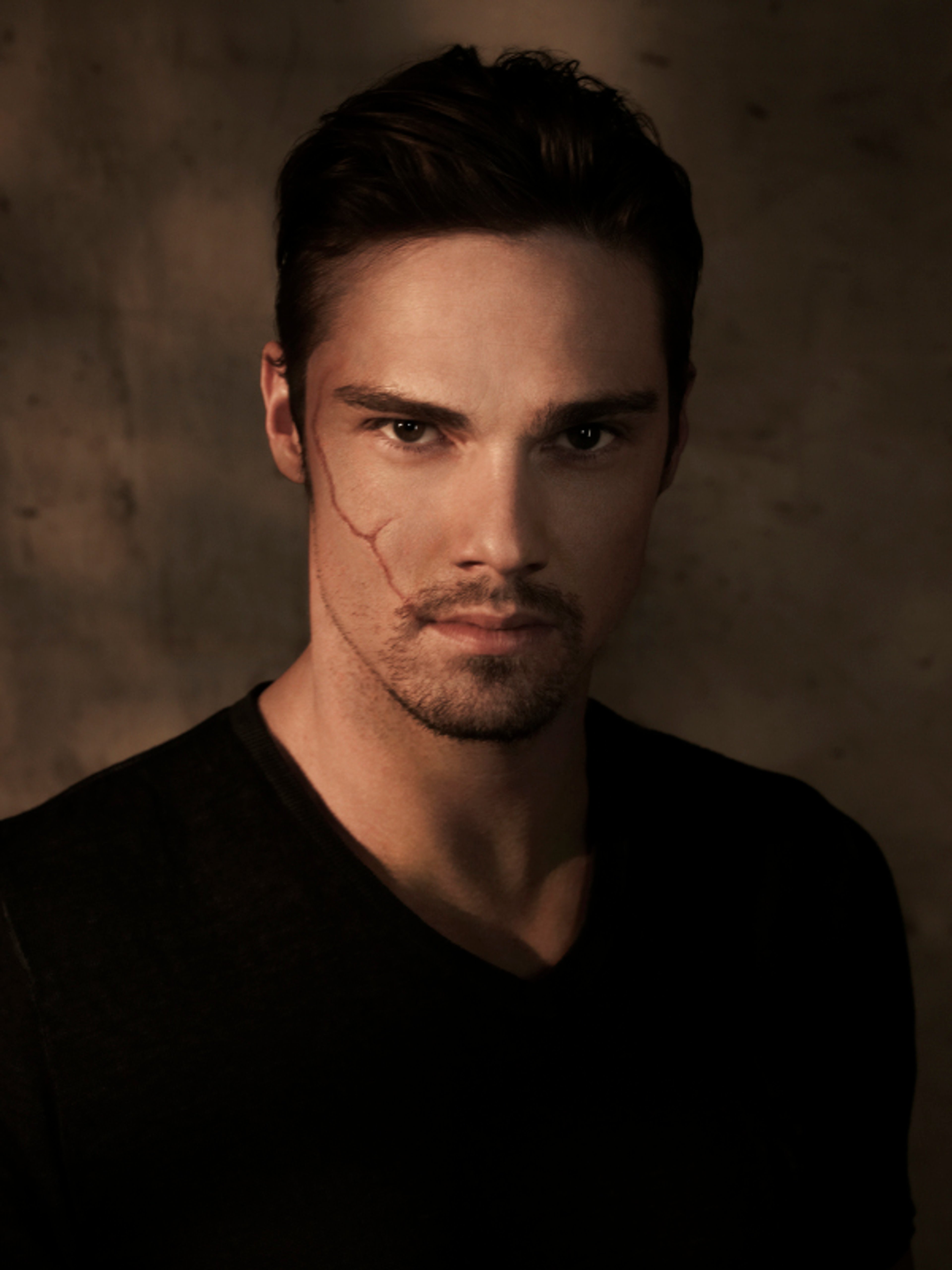 A close-up portrait of a serious-looking man with dark hair and a dramatic lighting setup.