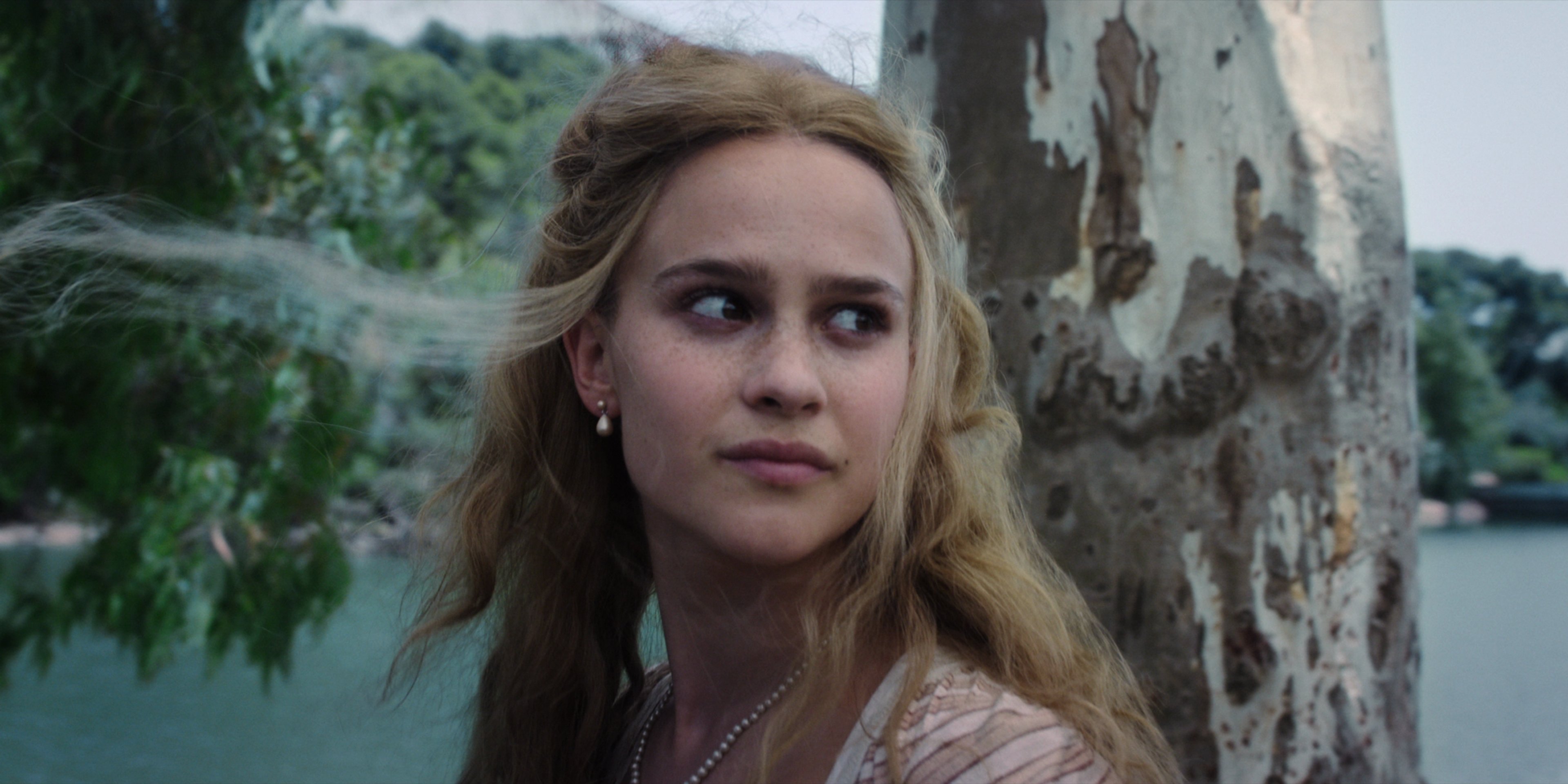 A young woman with long blonde hair standing in a natural setting