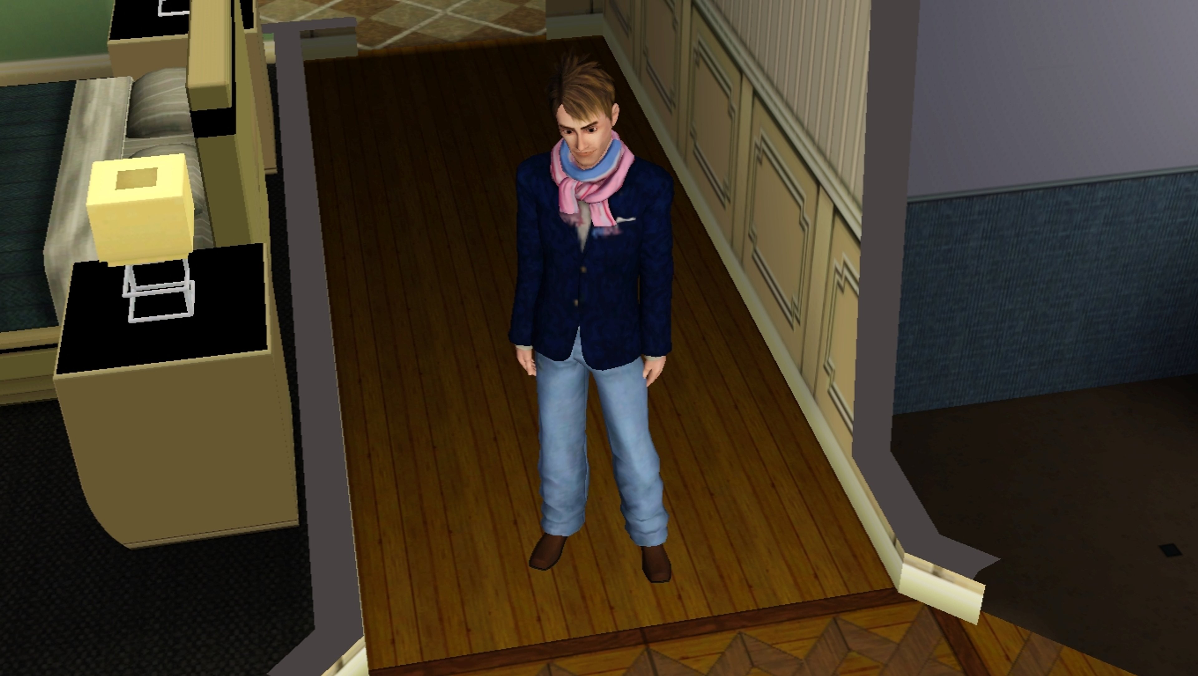 A young man in a navy blue suit jacket and jeans standing in a hallway or entryway.