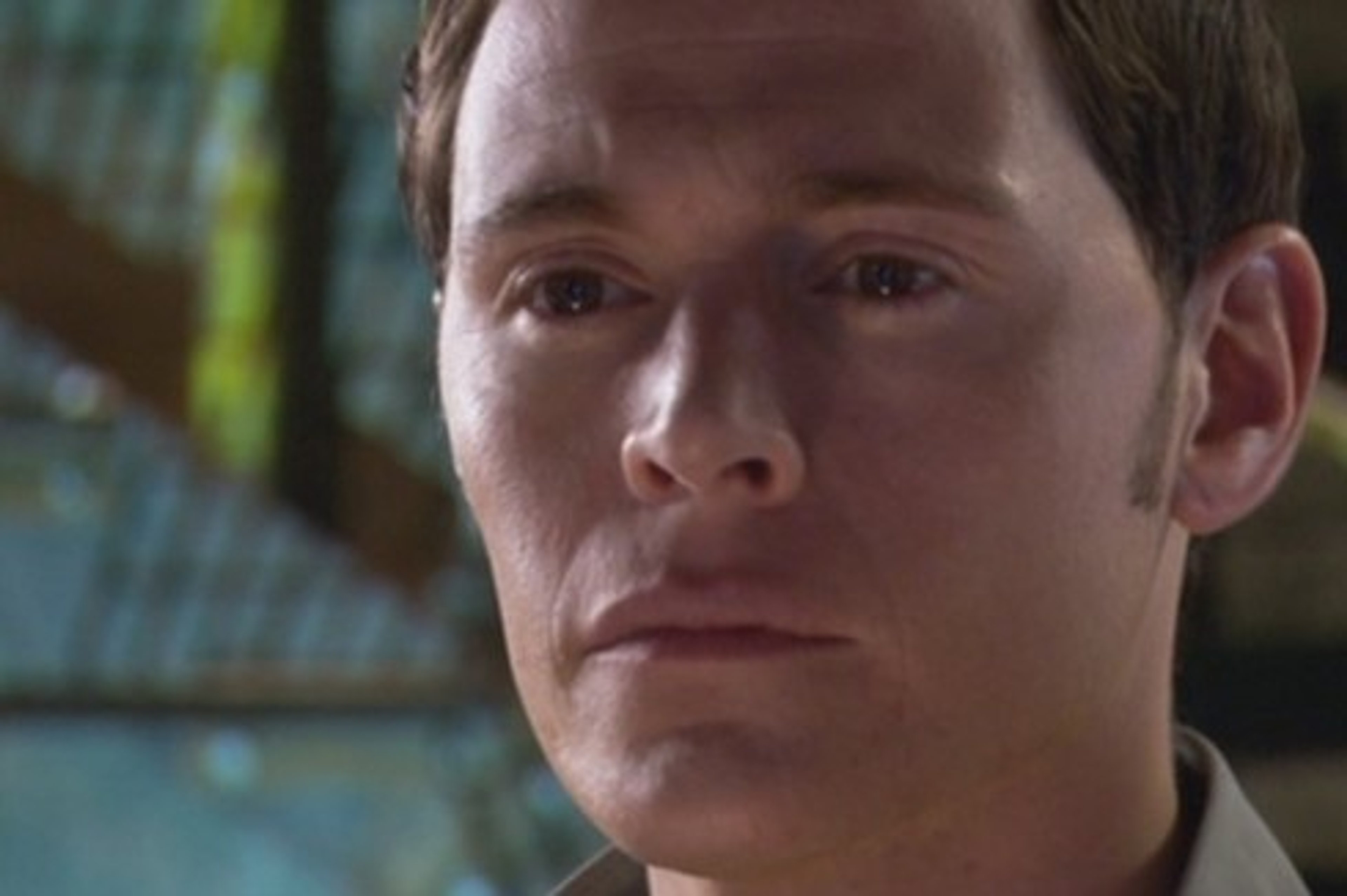 A young man with short dark hair and a serious expression