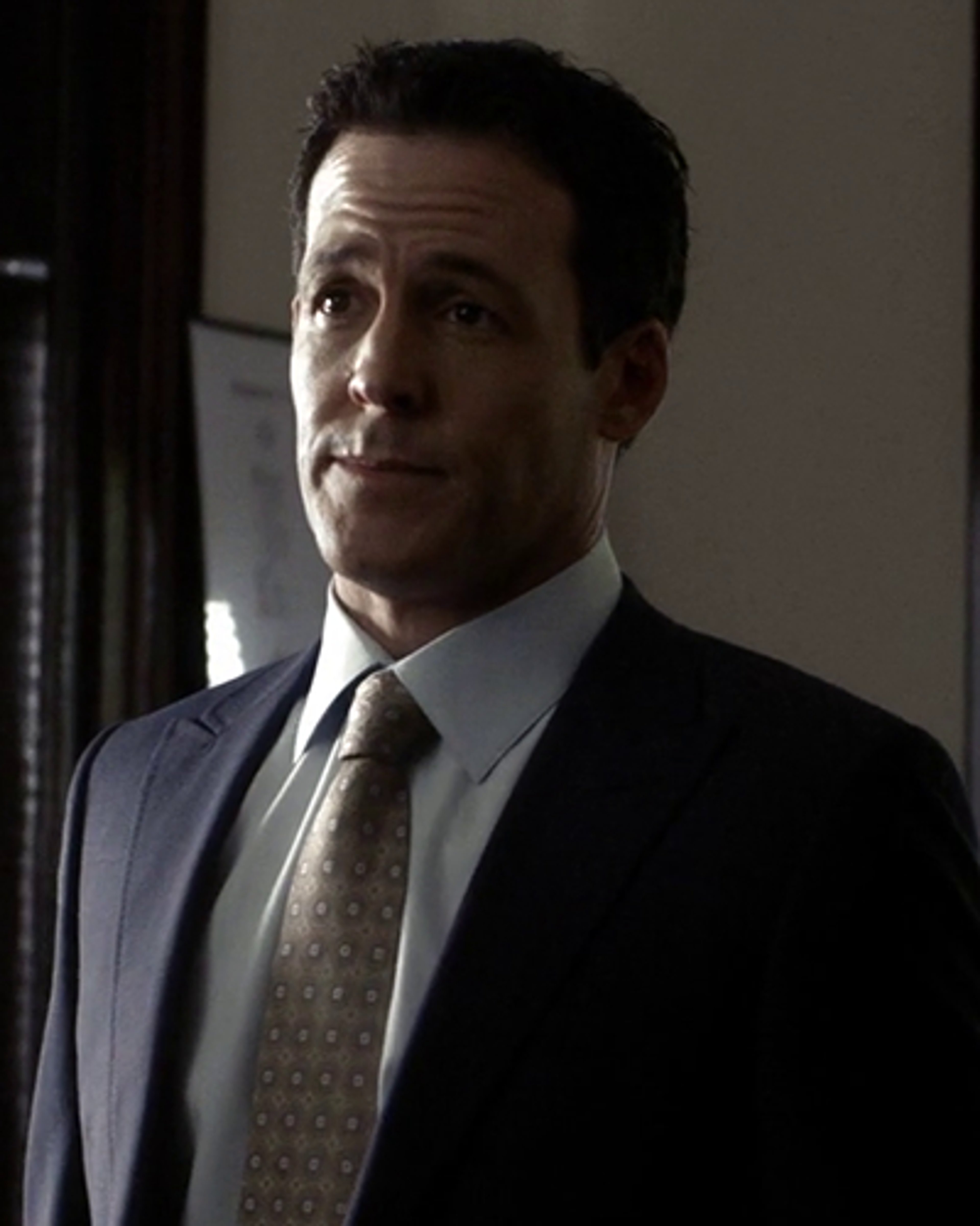 A middle-aged man in a suit and tie, with a serious expression