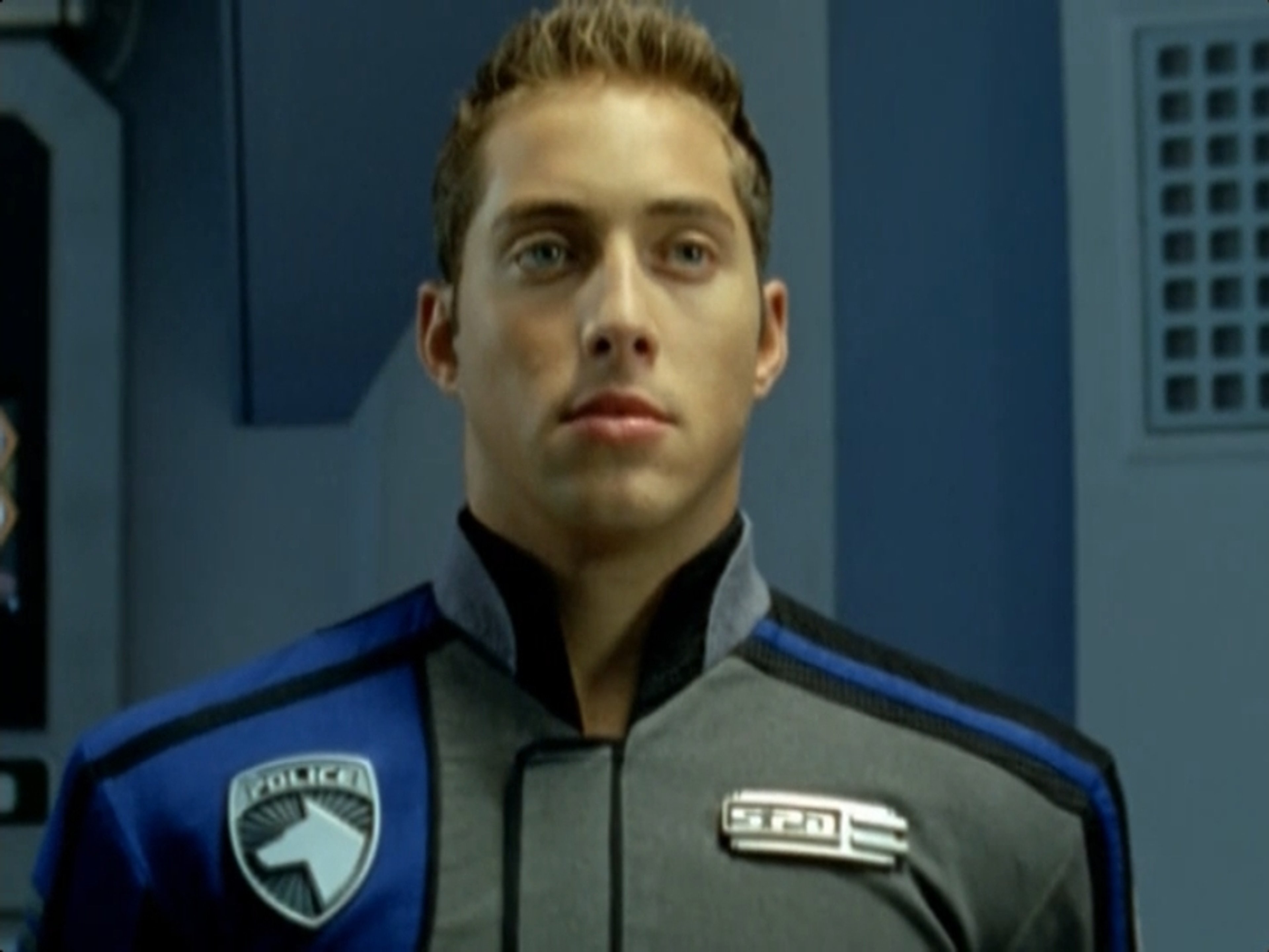 A young man in a blue police uniform standing in a police station