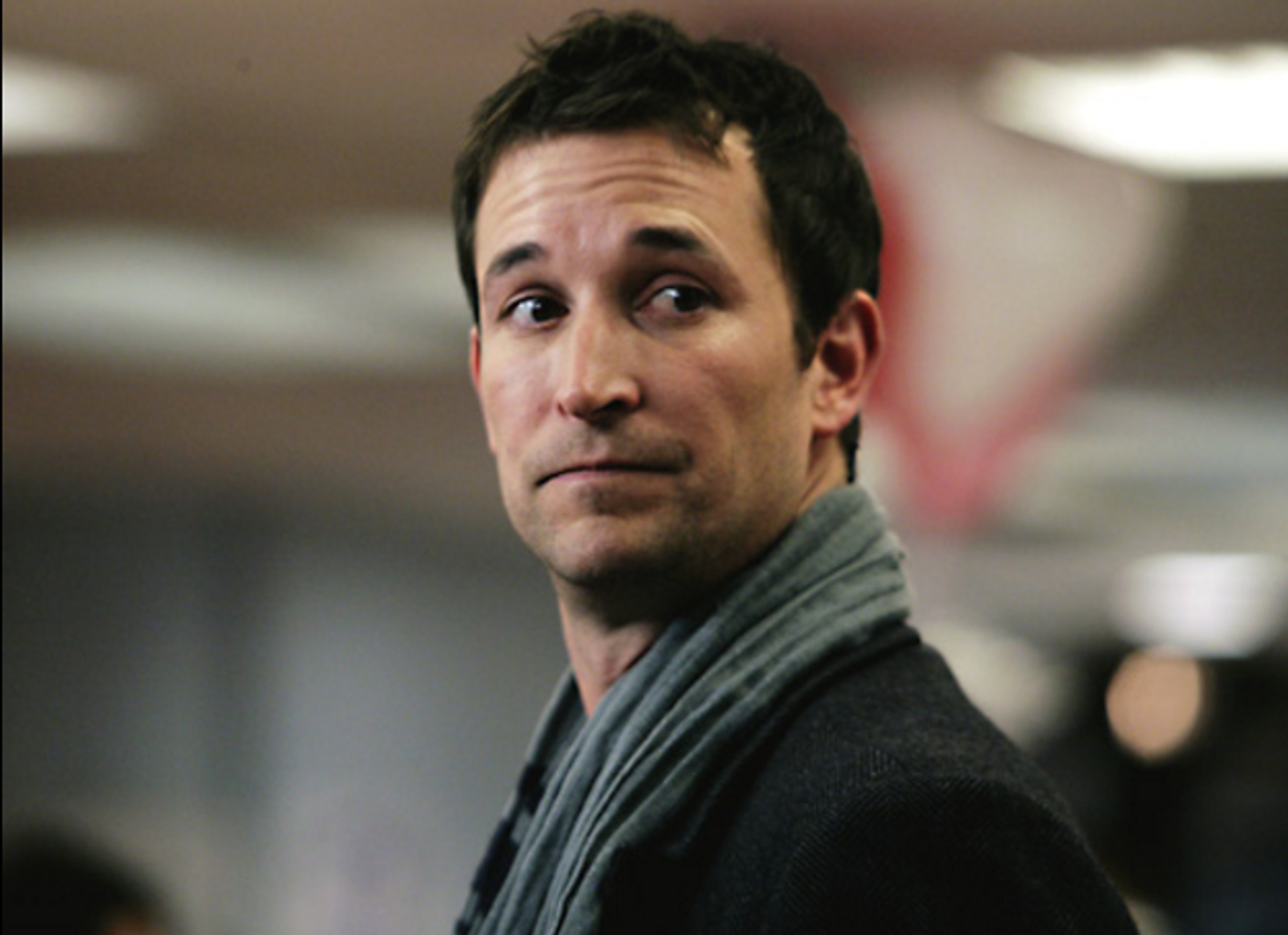 A middle-aged man in a gray sweater with a serious expression, likely a medical professional