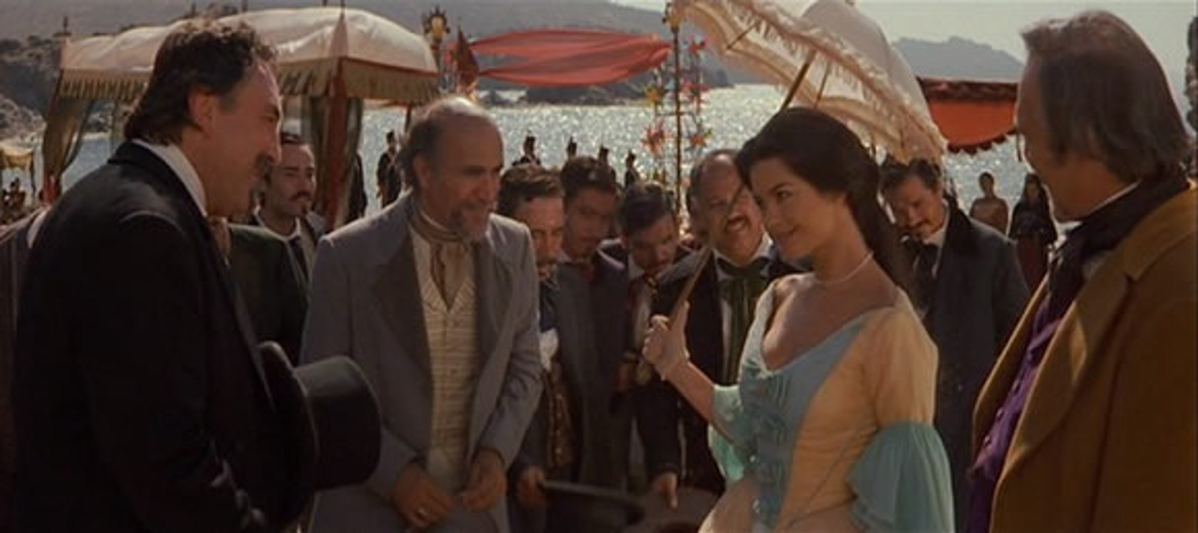 A group of people in formal attire, with a woman in a white dress as the central focus.