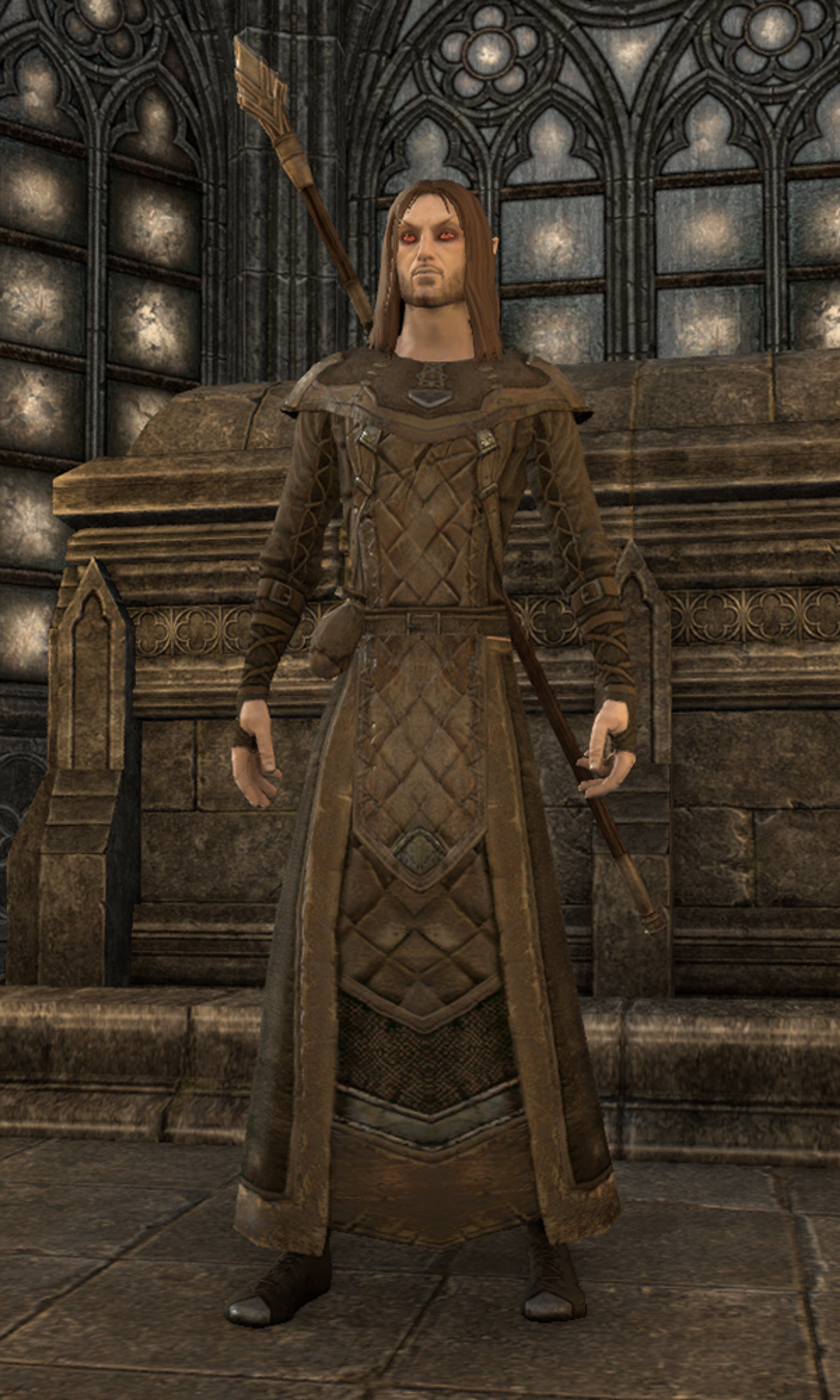 A tall, pale-skinned Altmer man wearing an ornate, diamond-patterned robe or cloak, standing in a grand, castle-like setting.