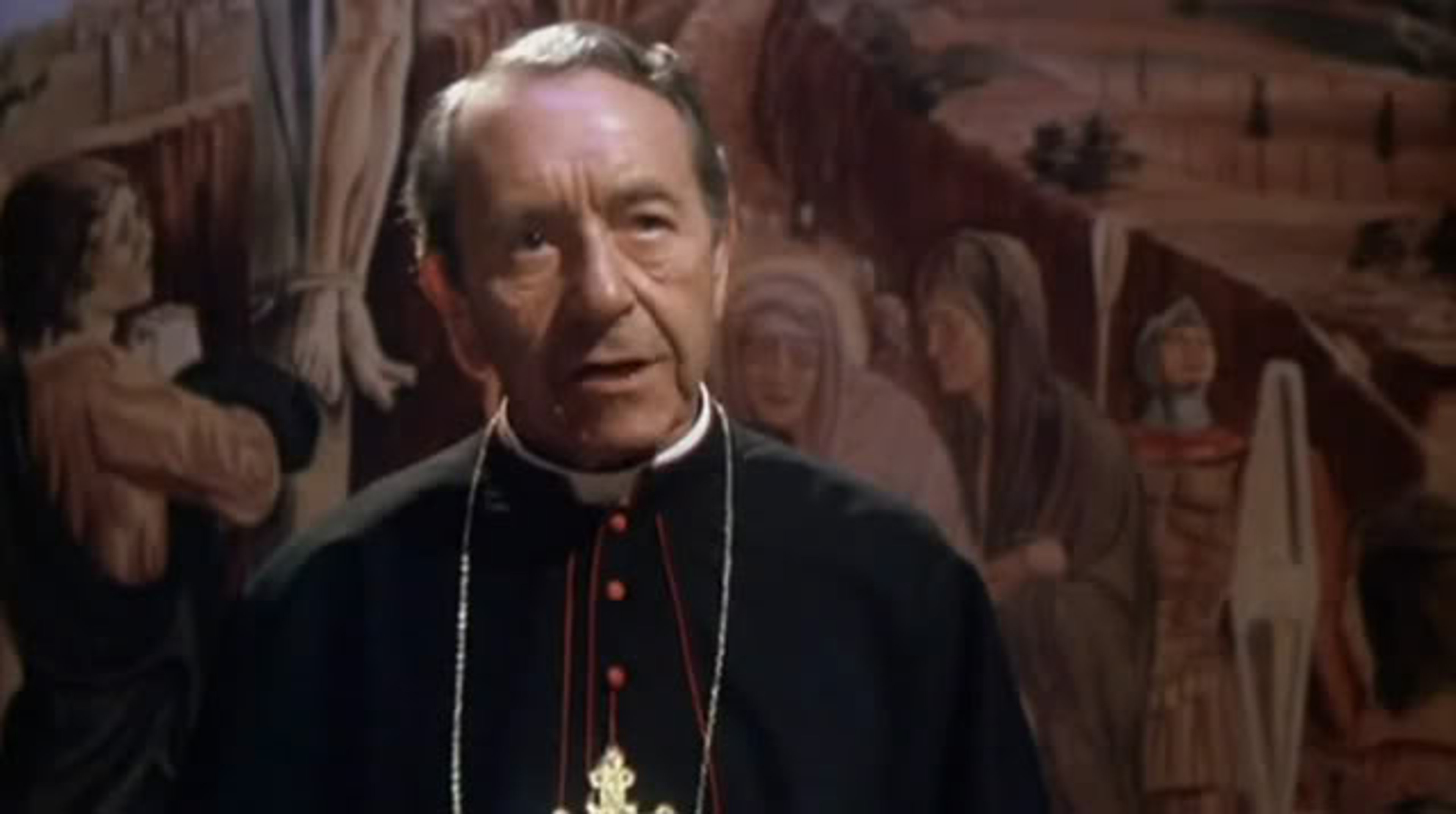 An elderly man wearing a red cardinal's robe and hat, with a stern, thoughtful expression.