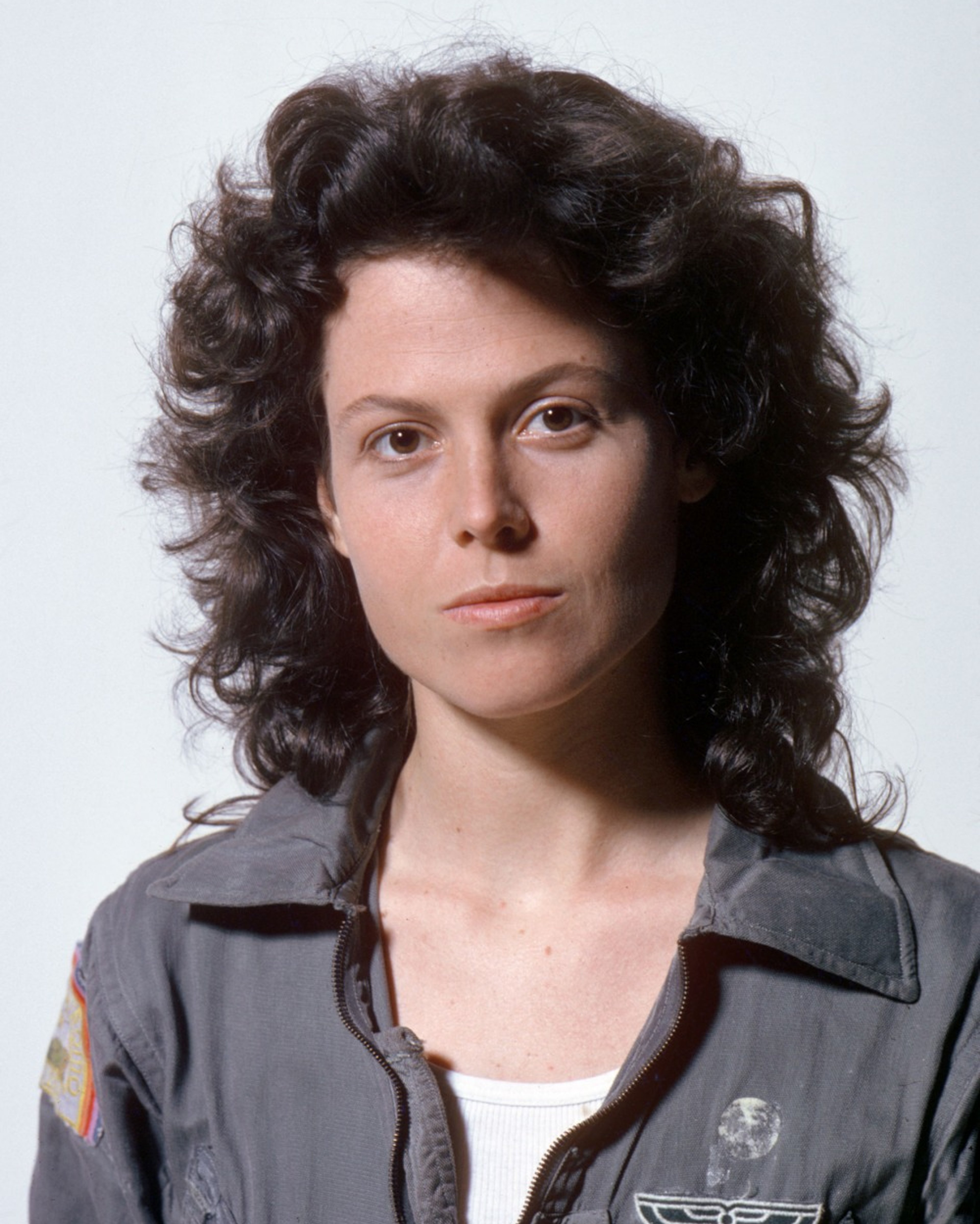 A woman with curly dark hair wearing a gray jacket