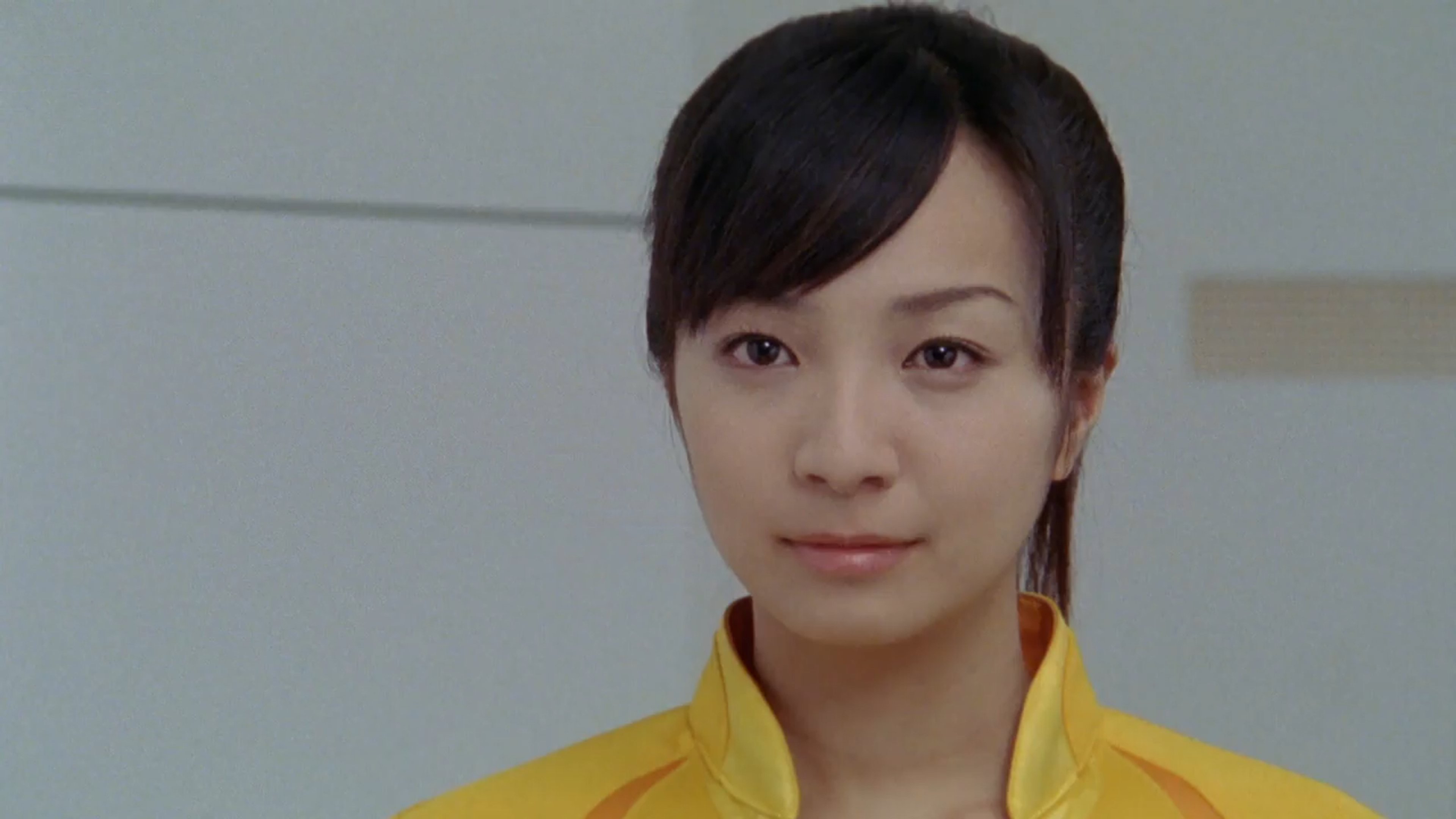 A young woman with short dark hair wearing a yellow jacket