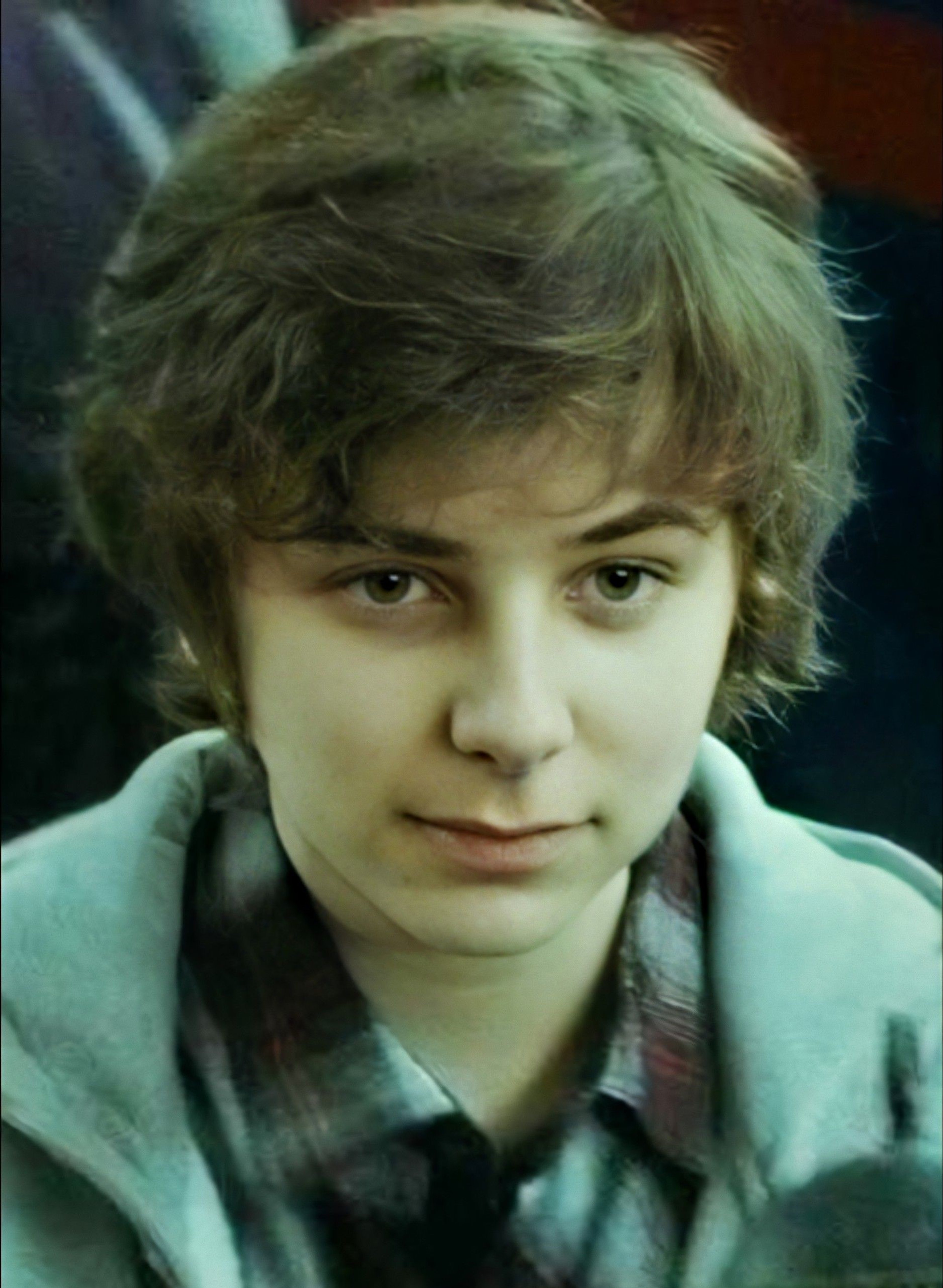 A young boy with messy brown hair and a friendly expression