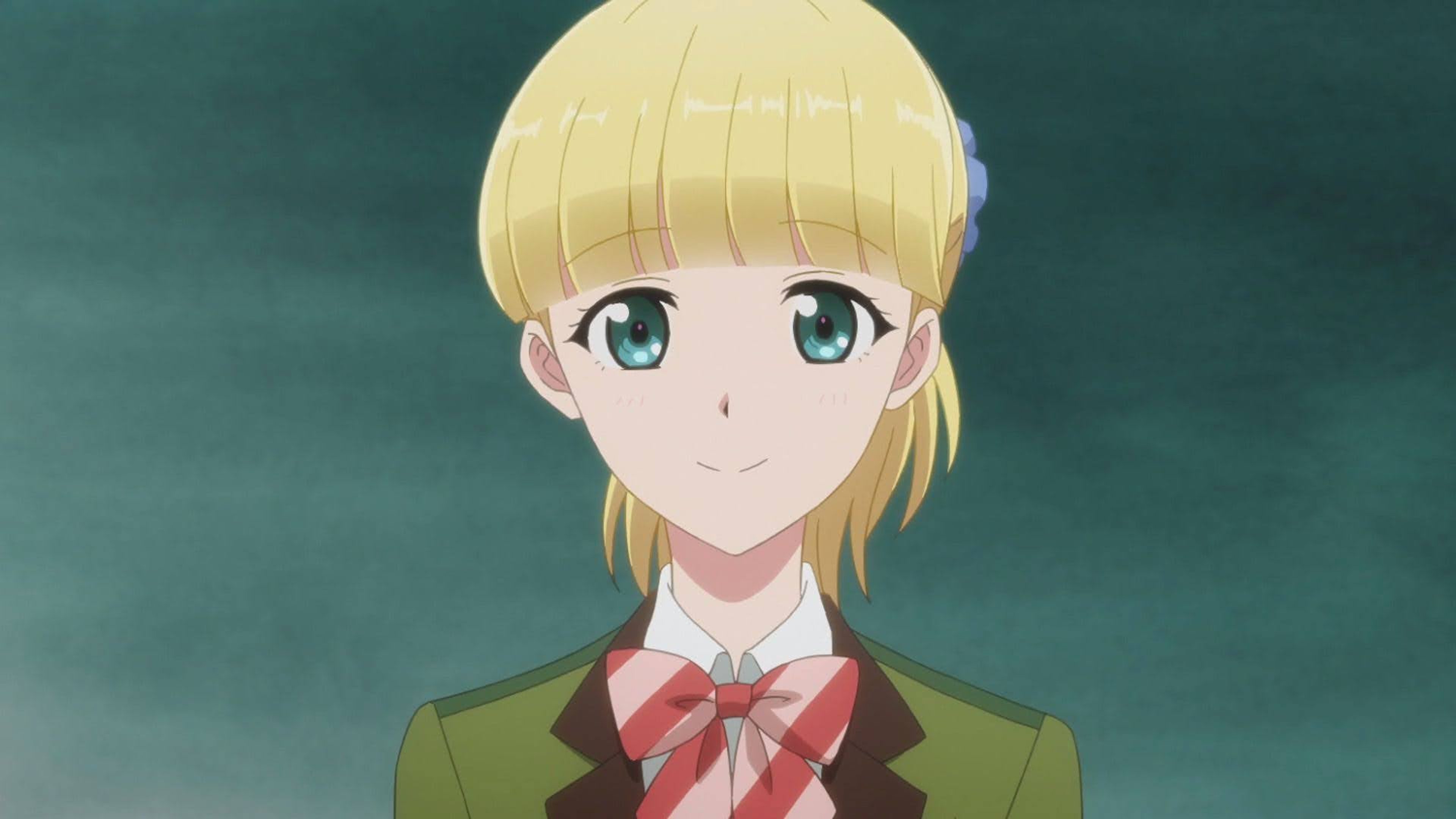 A young woman with blonde hair and blue eyes wearing a red bow tie and green jacket.