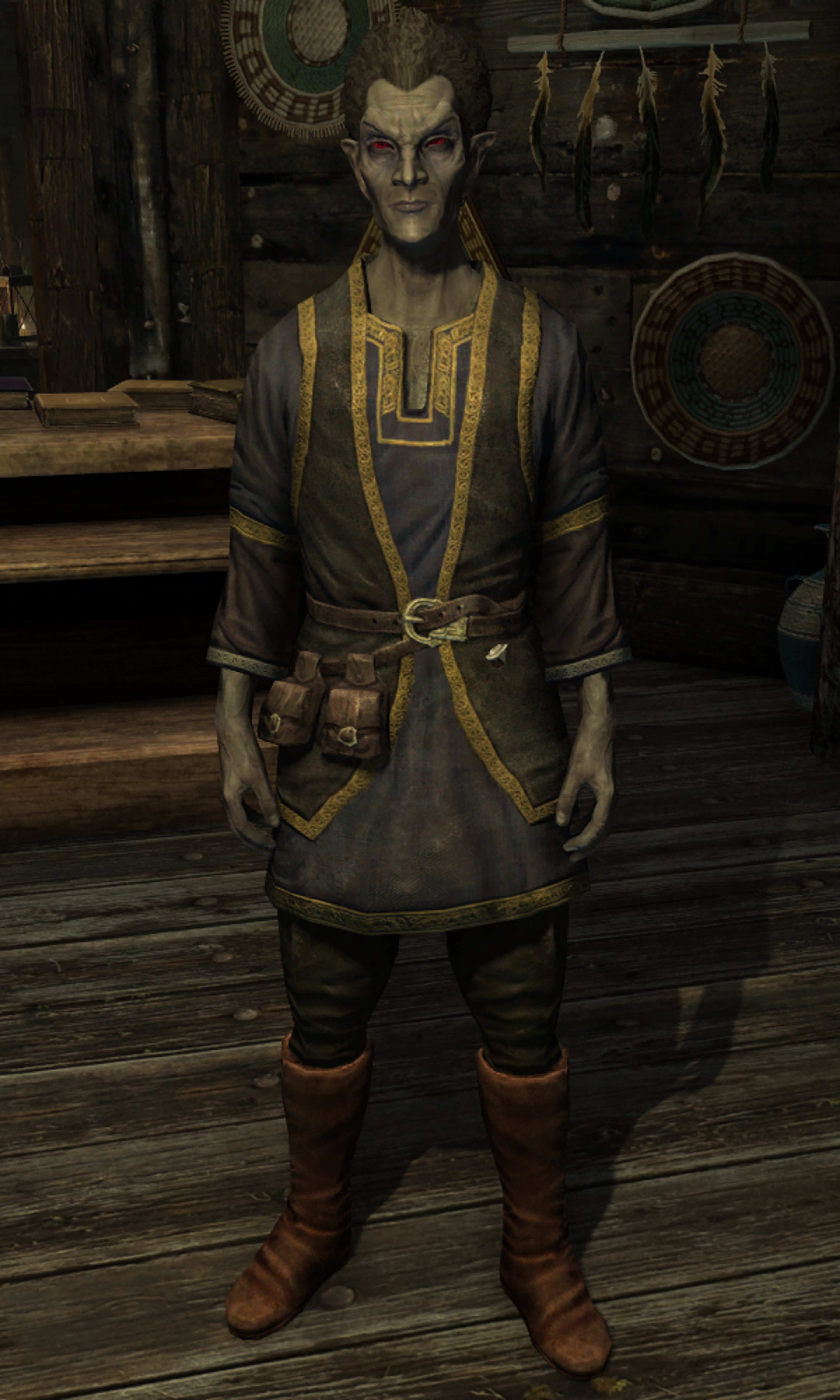 A Dunmer male character wearing a gray and gold outfit, standing in a shop or merchant's stall.