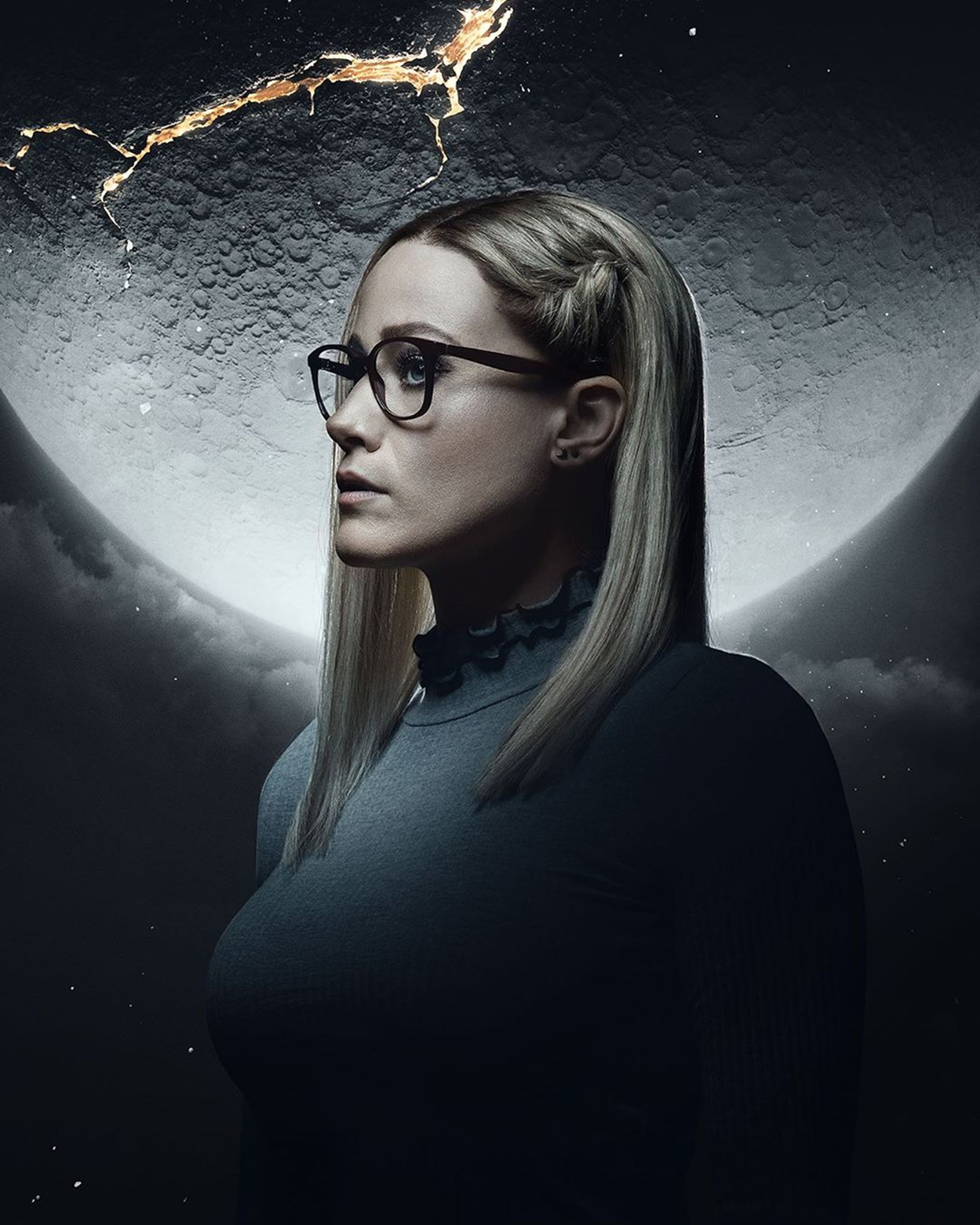 A young woman with blonde hair and glasses looking thoughtful against a dark, moody background