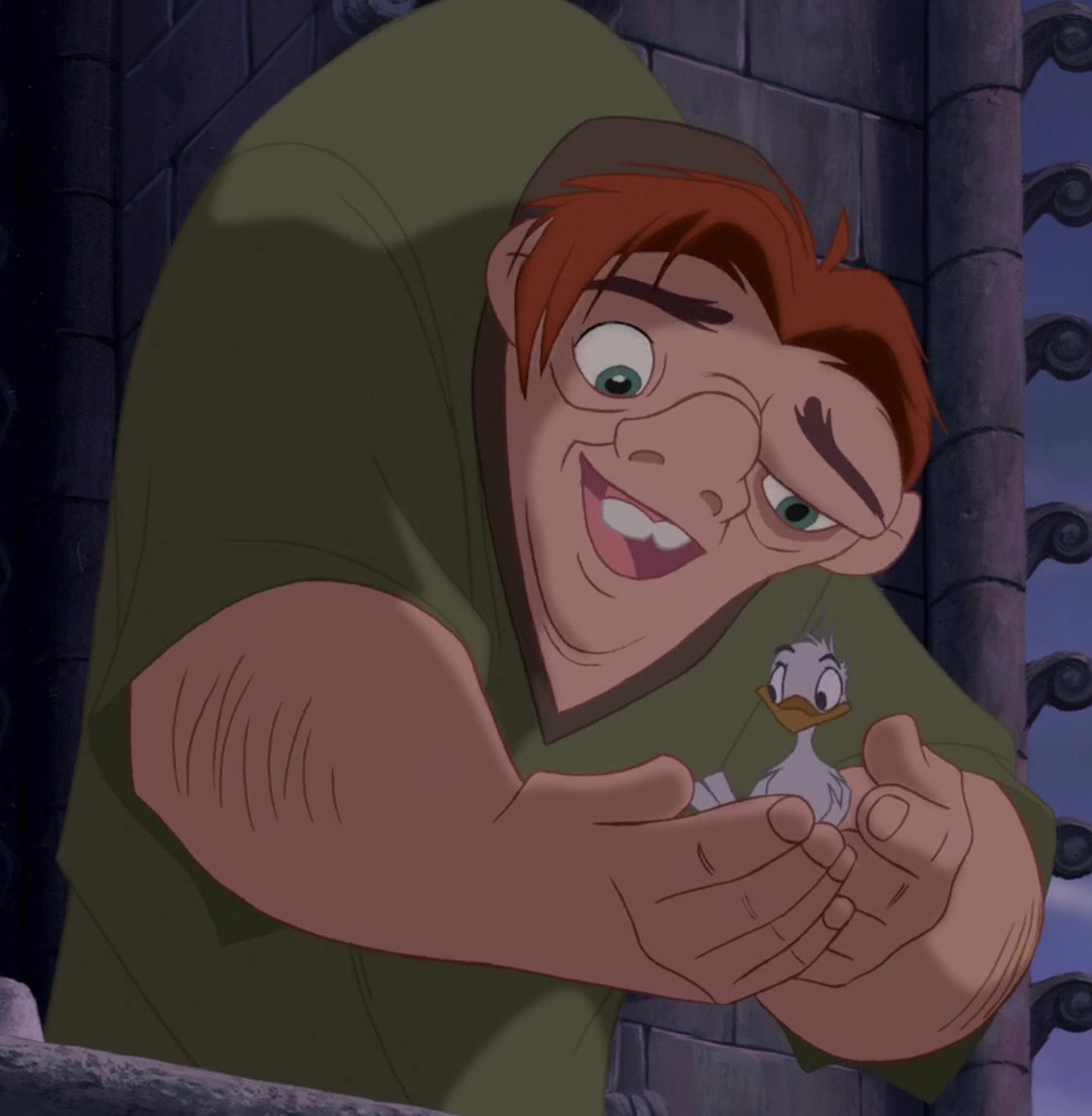 A character with a deformed, hunched back and large head, wearing a green cloak and smiling.