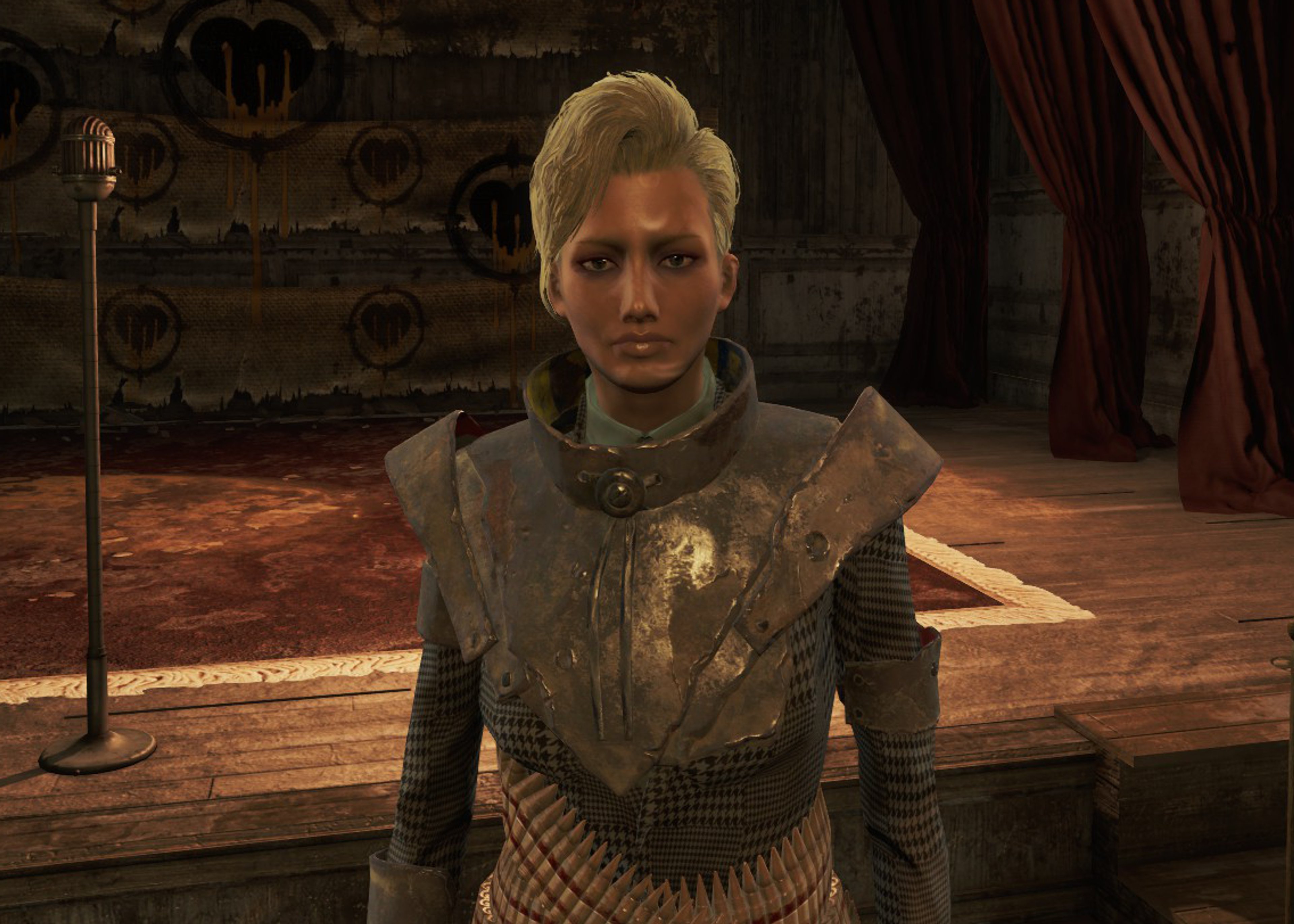 A woman with blonde hair wearing a gray outfit in a dimly lit room