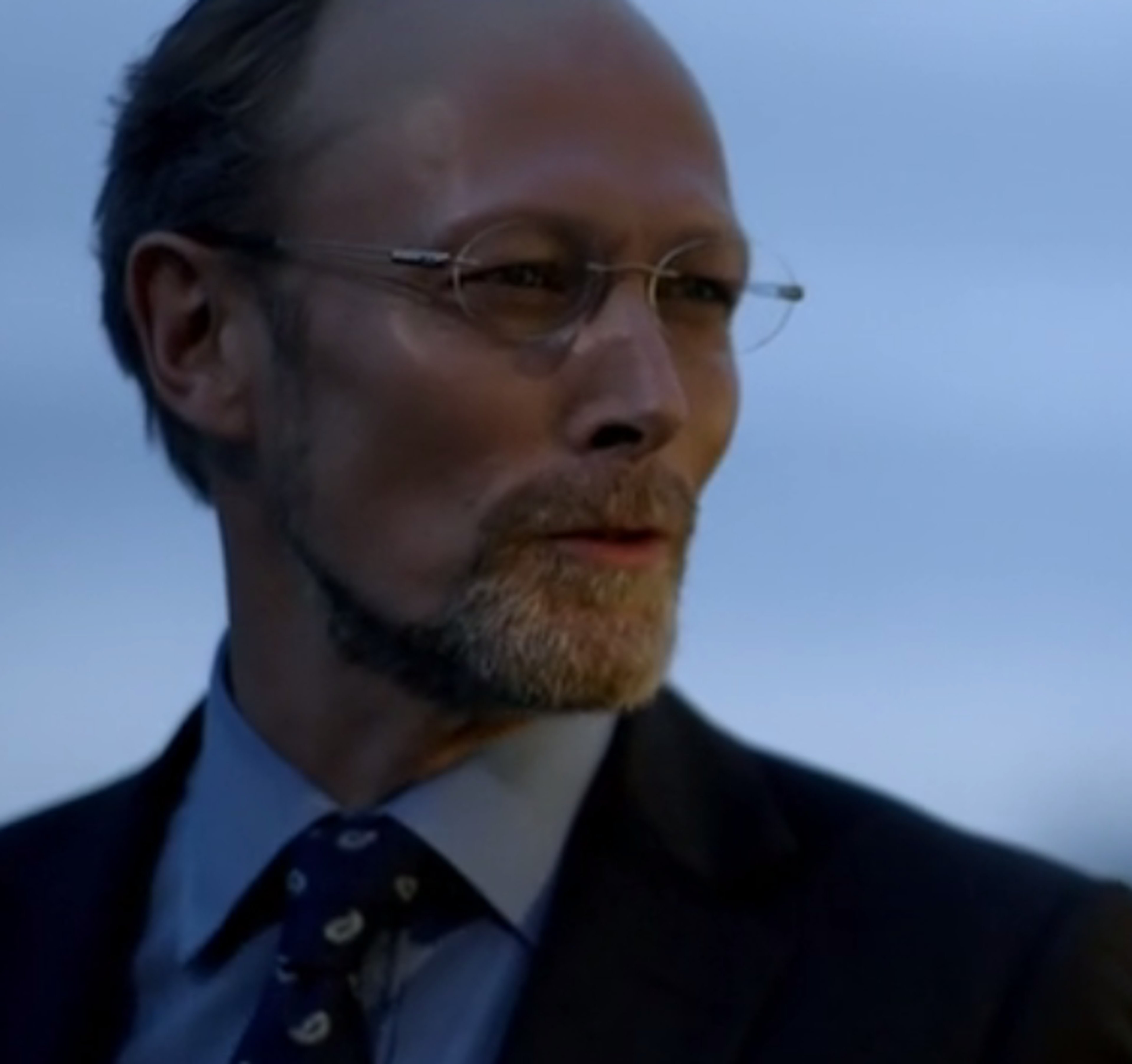 A middle-aged man in a suit and tie with a stern expression