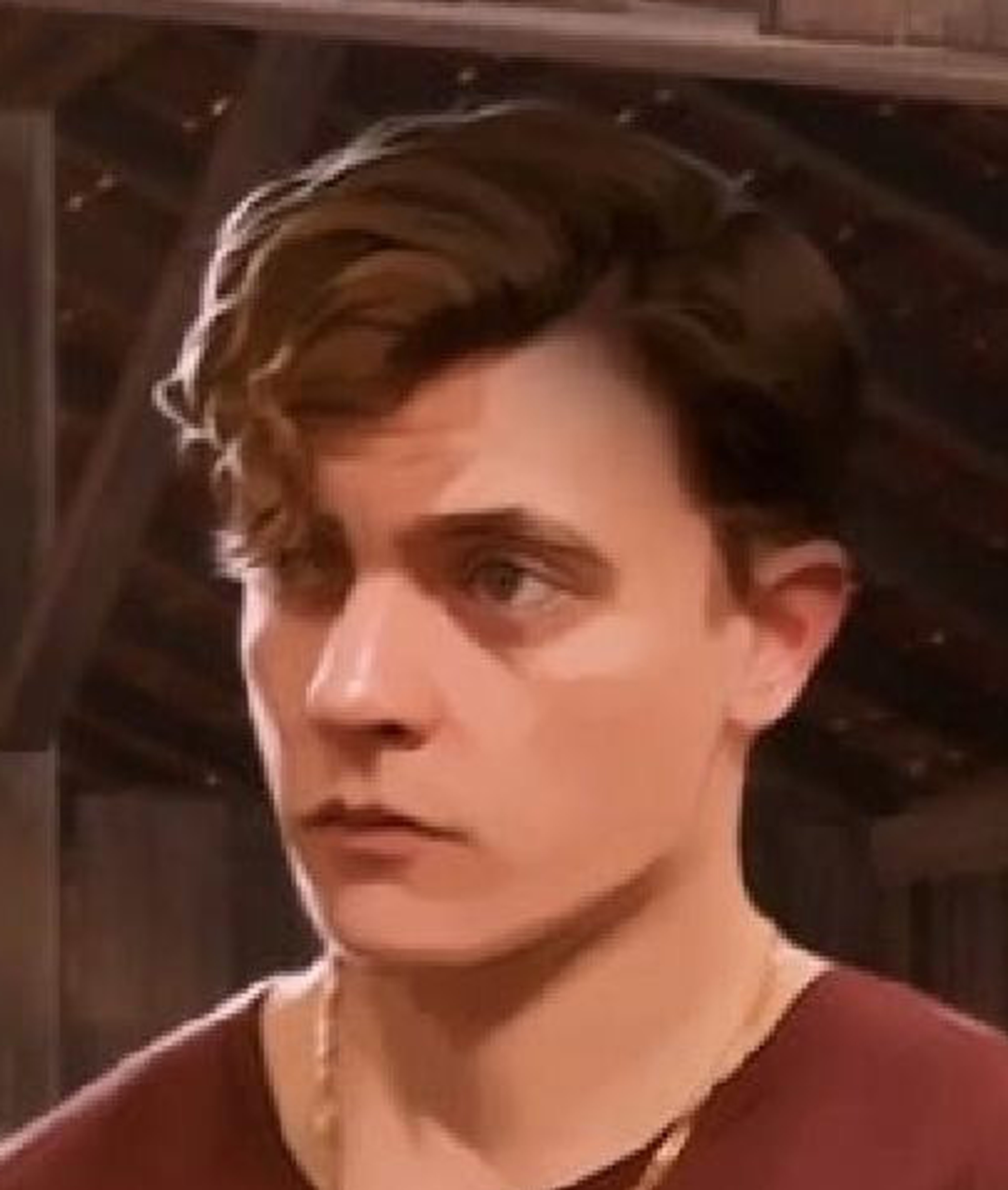 A young man with dark hair and a confident expression, wearing a black and white shirt and jeans.