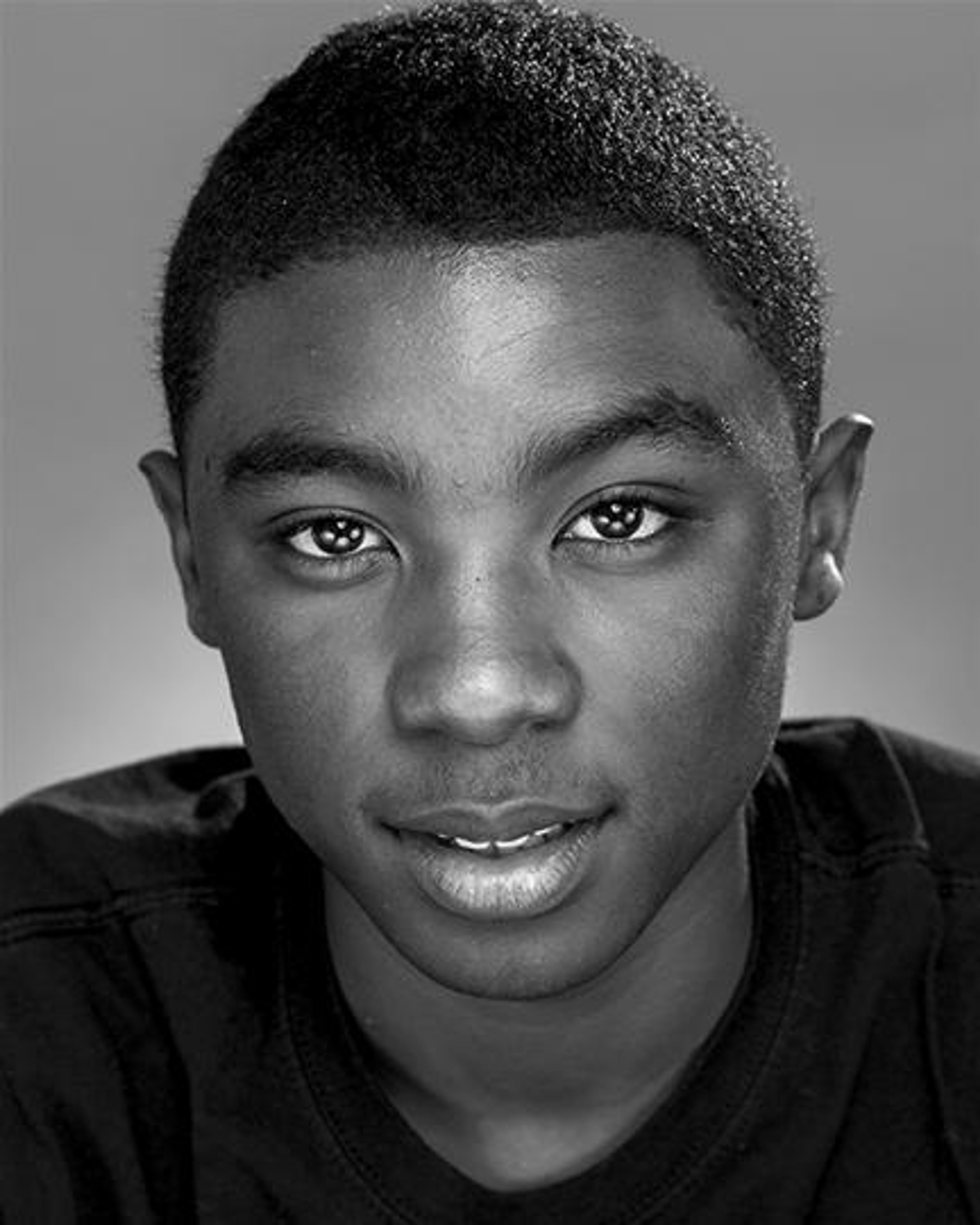 A close-up portrait of a young Black man with a serious expression