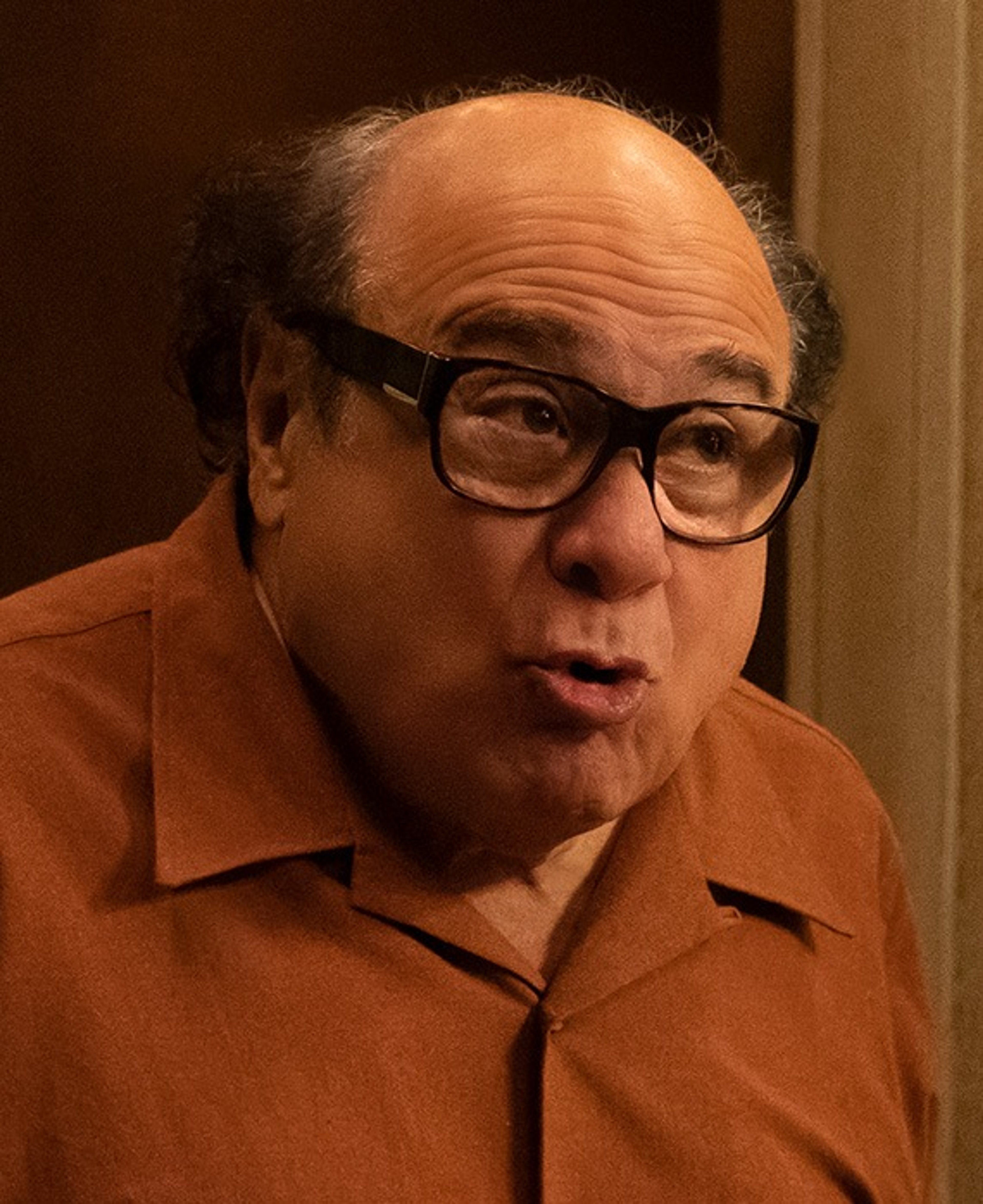 An older, bald man with glasses wearing a light-colored shirt