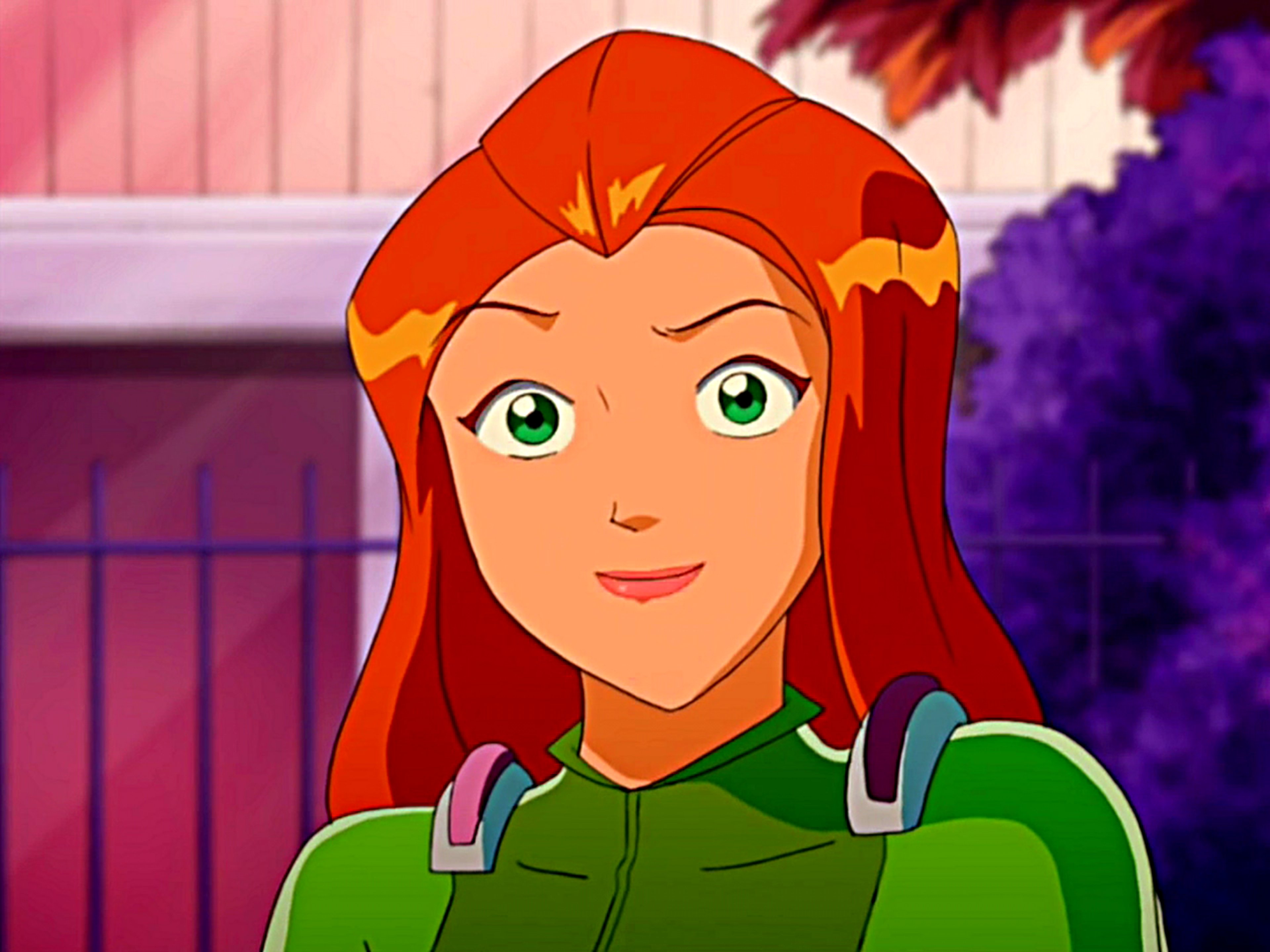 An animated female character with red hair and green eyes, wearing a green outfit with shoulder pads, looking friendly and confident.