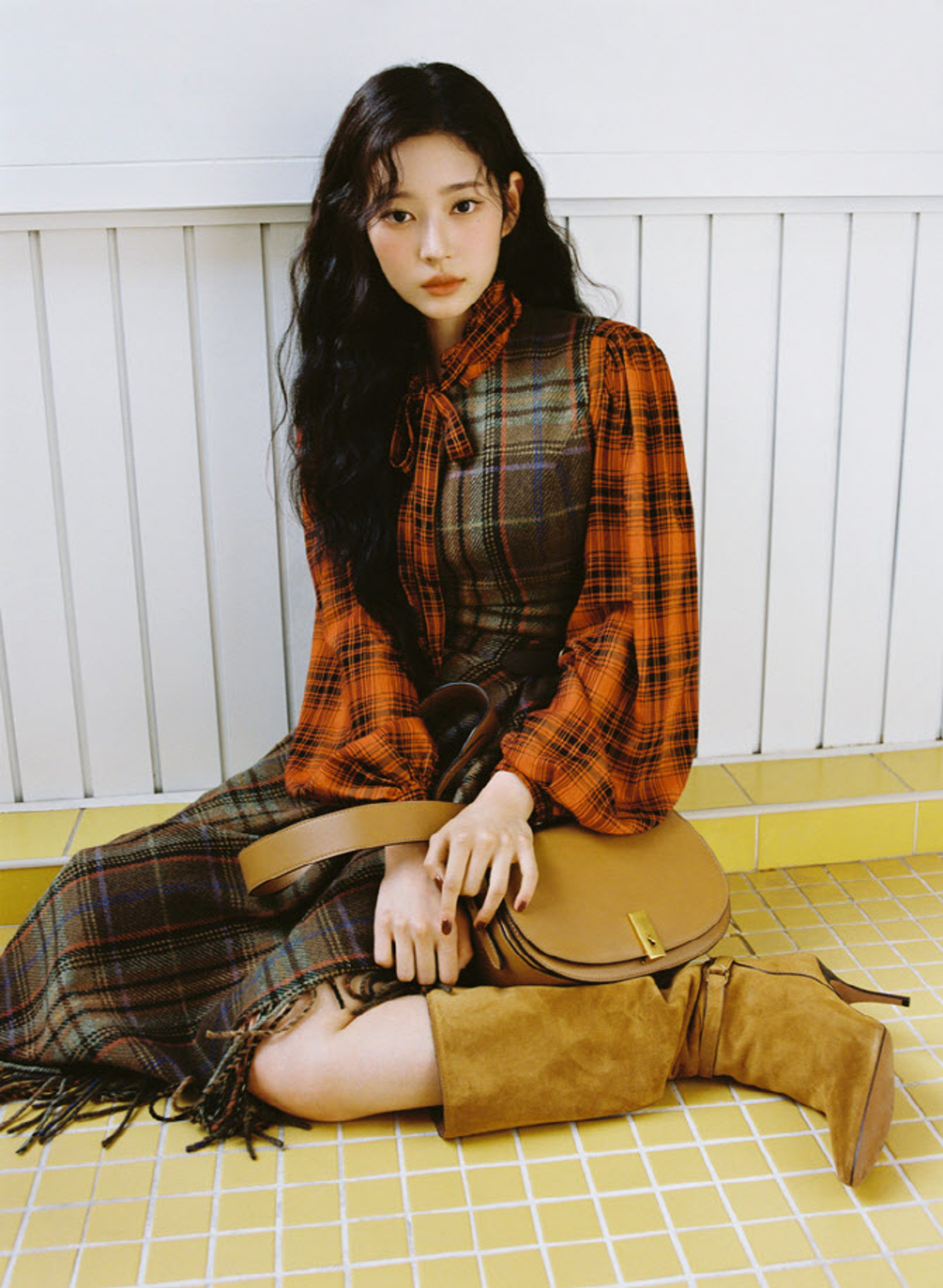 A young Korean woman with long dark hair sitting on the ground wearing a plaid shirt