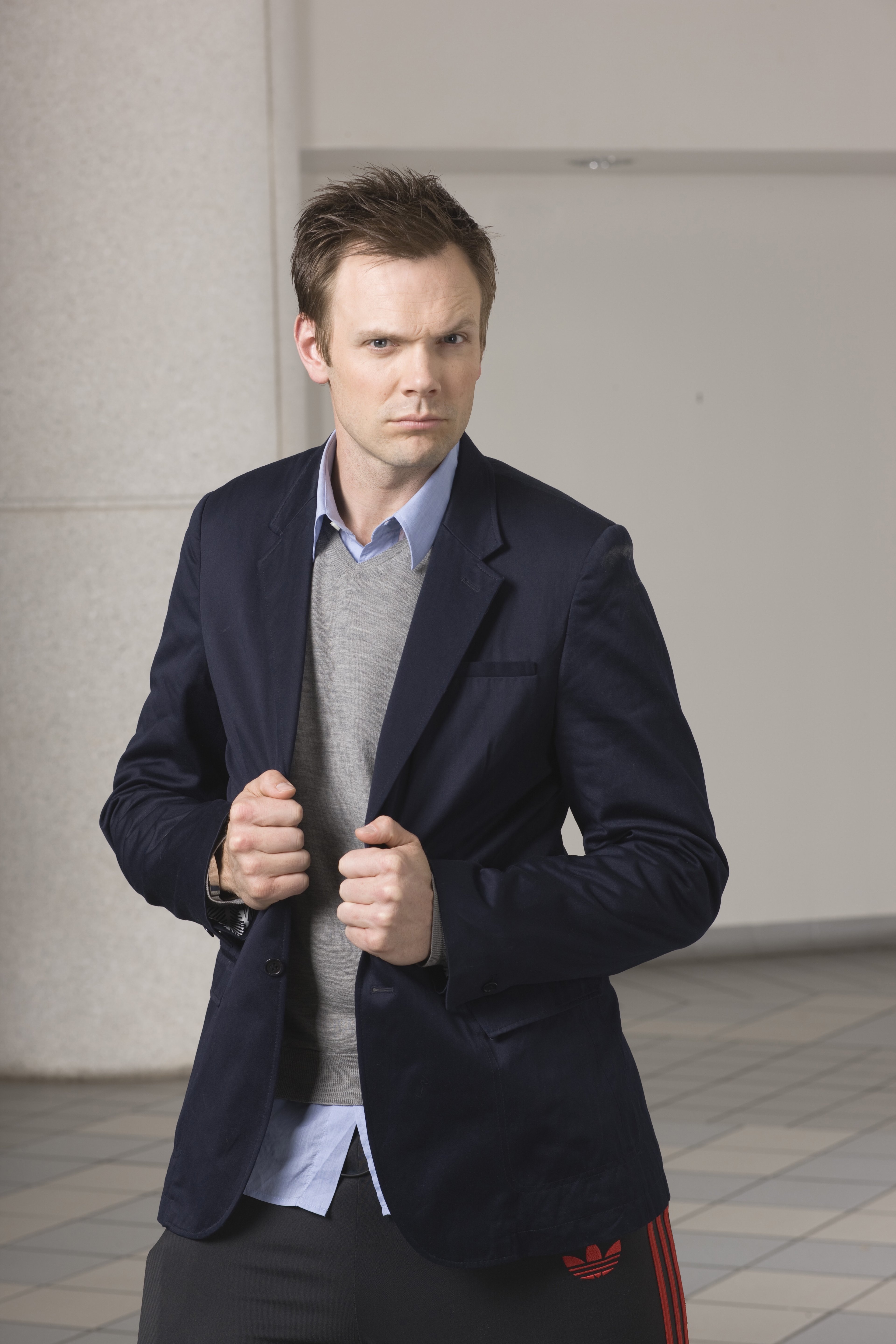 A man in a navy blue suit jacket and light blue shirt with a serious expression