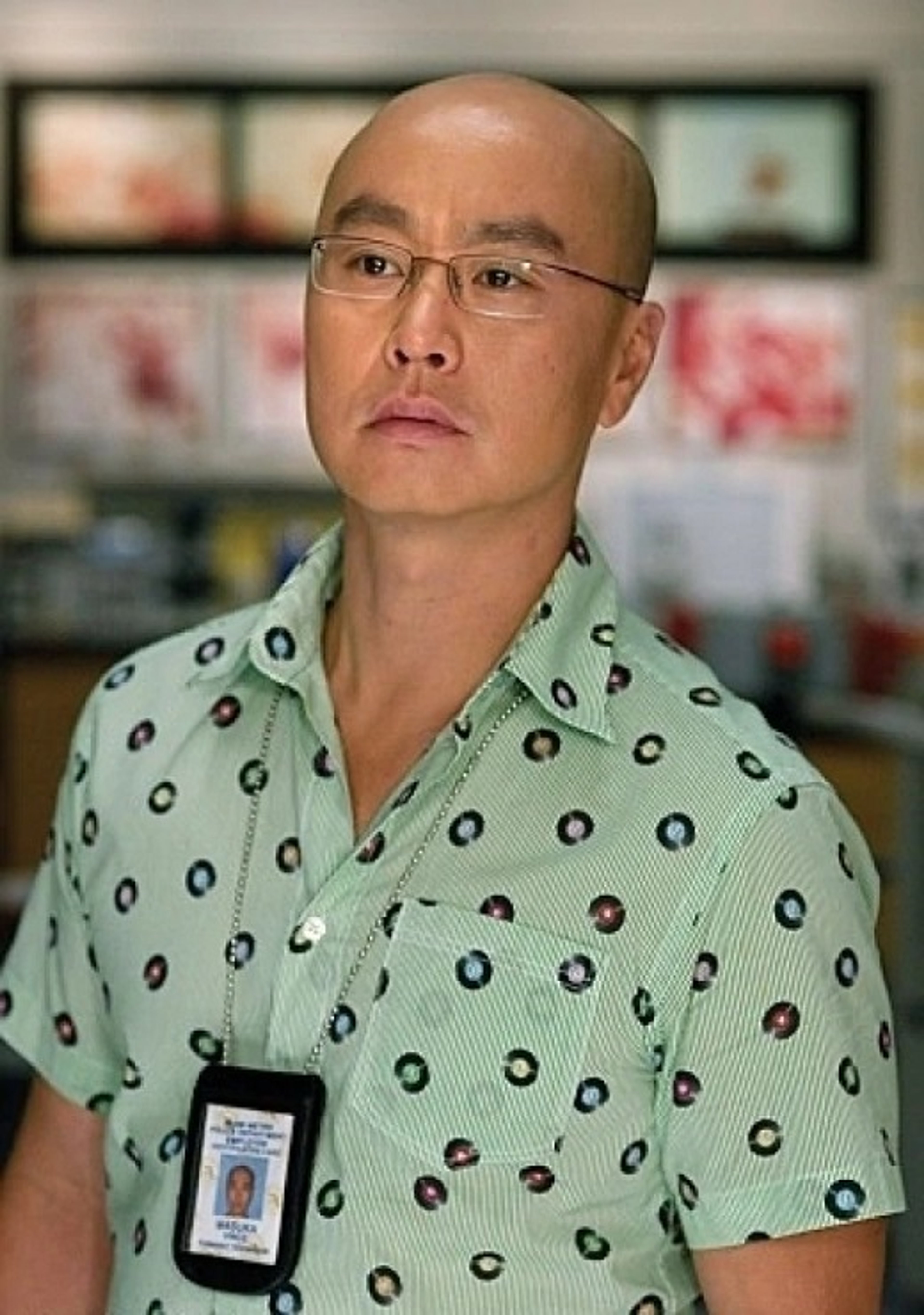 A middle-aged Asian man with a bald head and glasses, wearing a patterned shirt