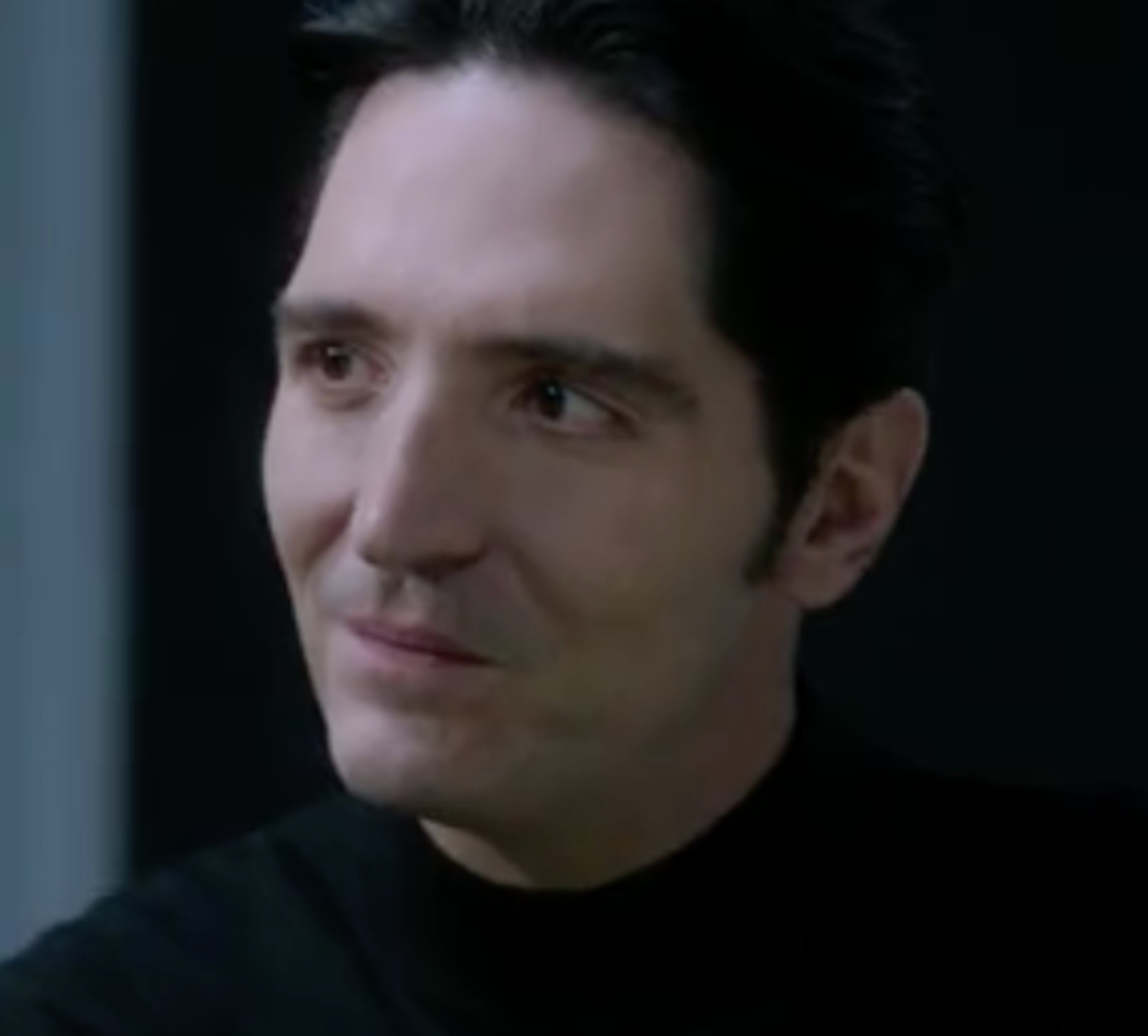 A serious-looking middle-aged man with dark hair and intense eyes