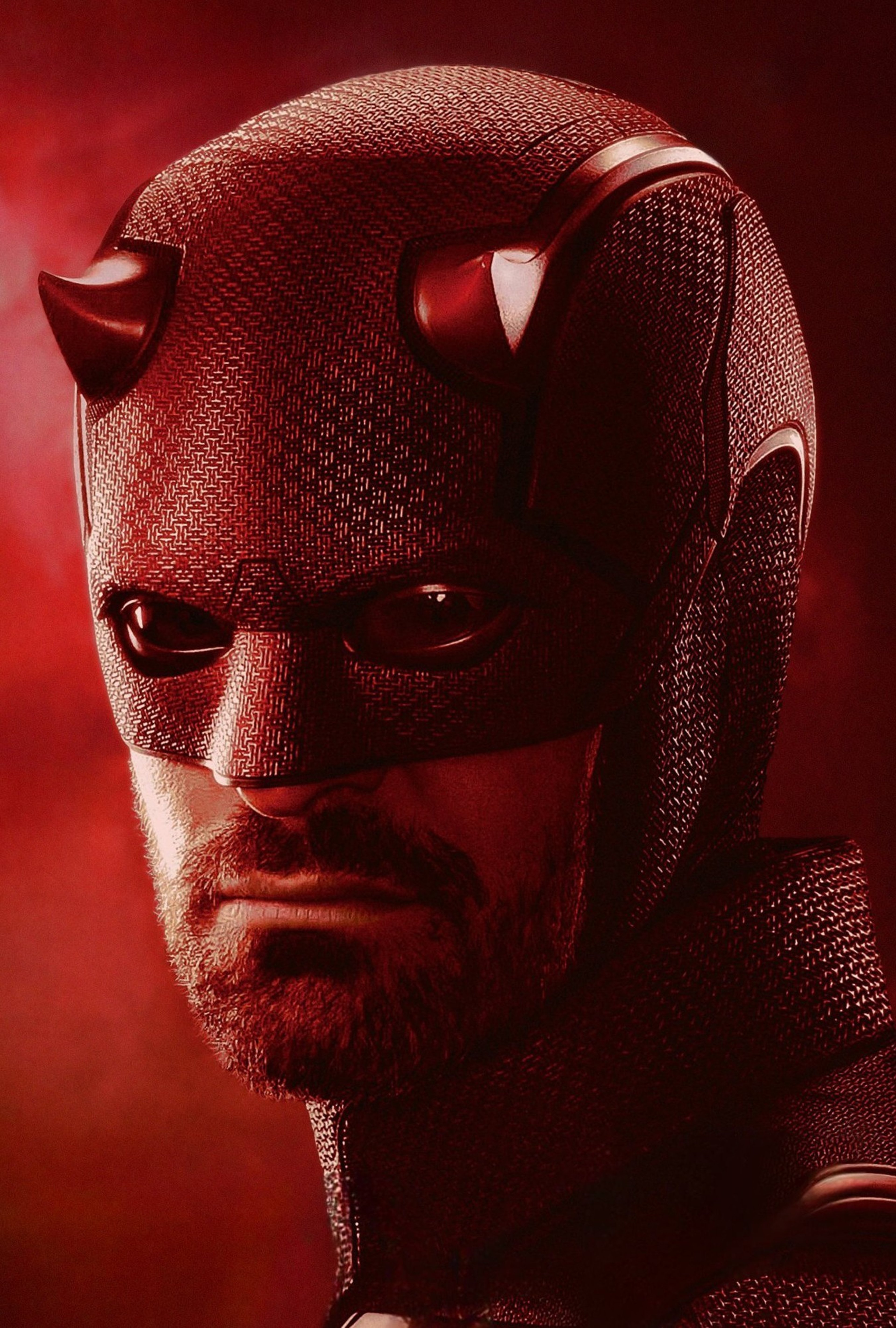 A close-up portrait of a man in a red superhero costume and mask, with a serious, intense expression on his face.