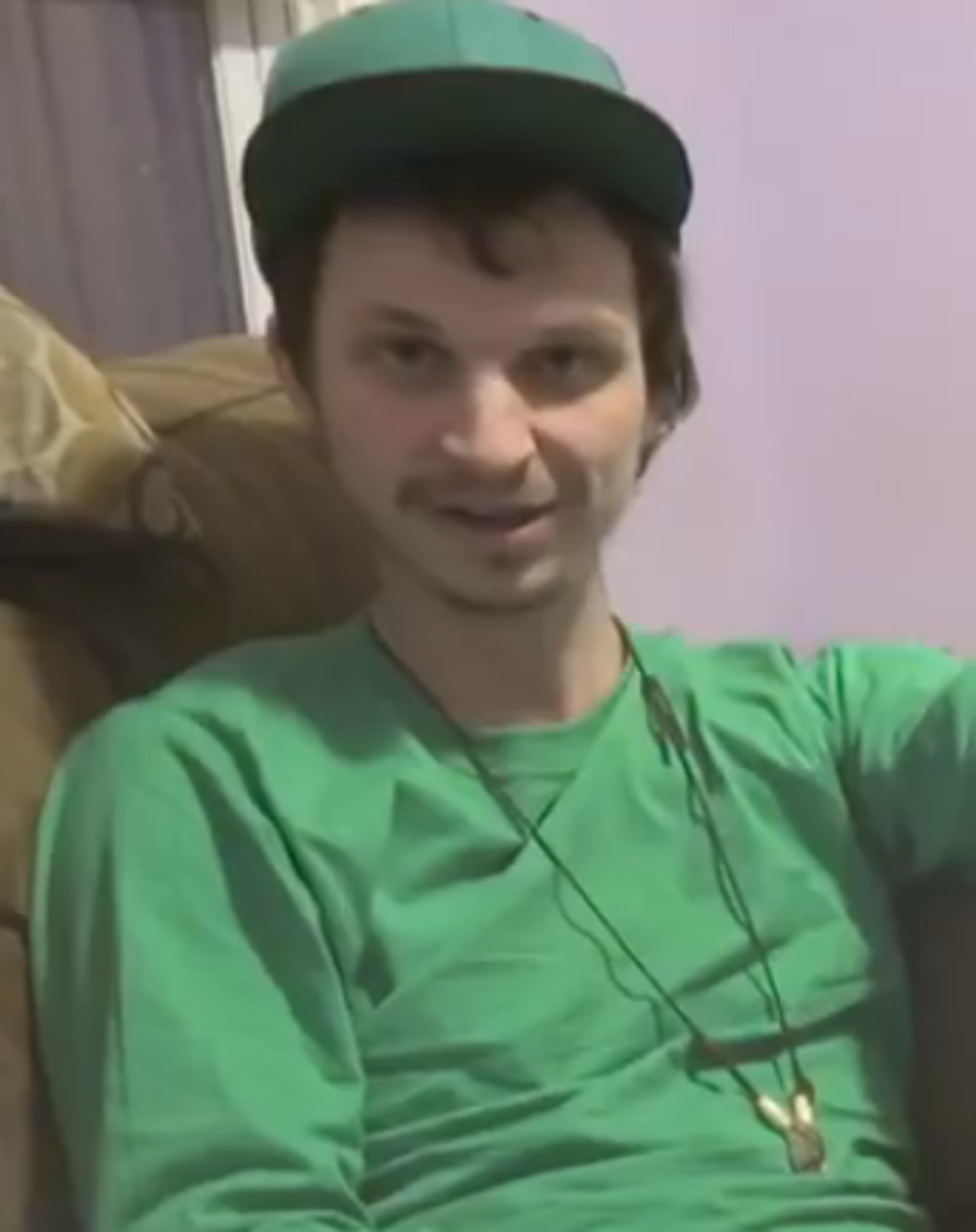 A young man with short dark hair and a green hat, smiling at the camera.