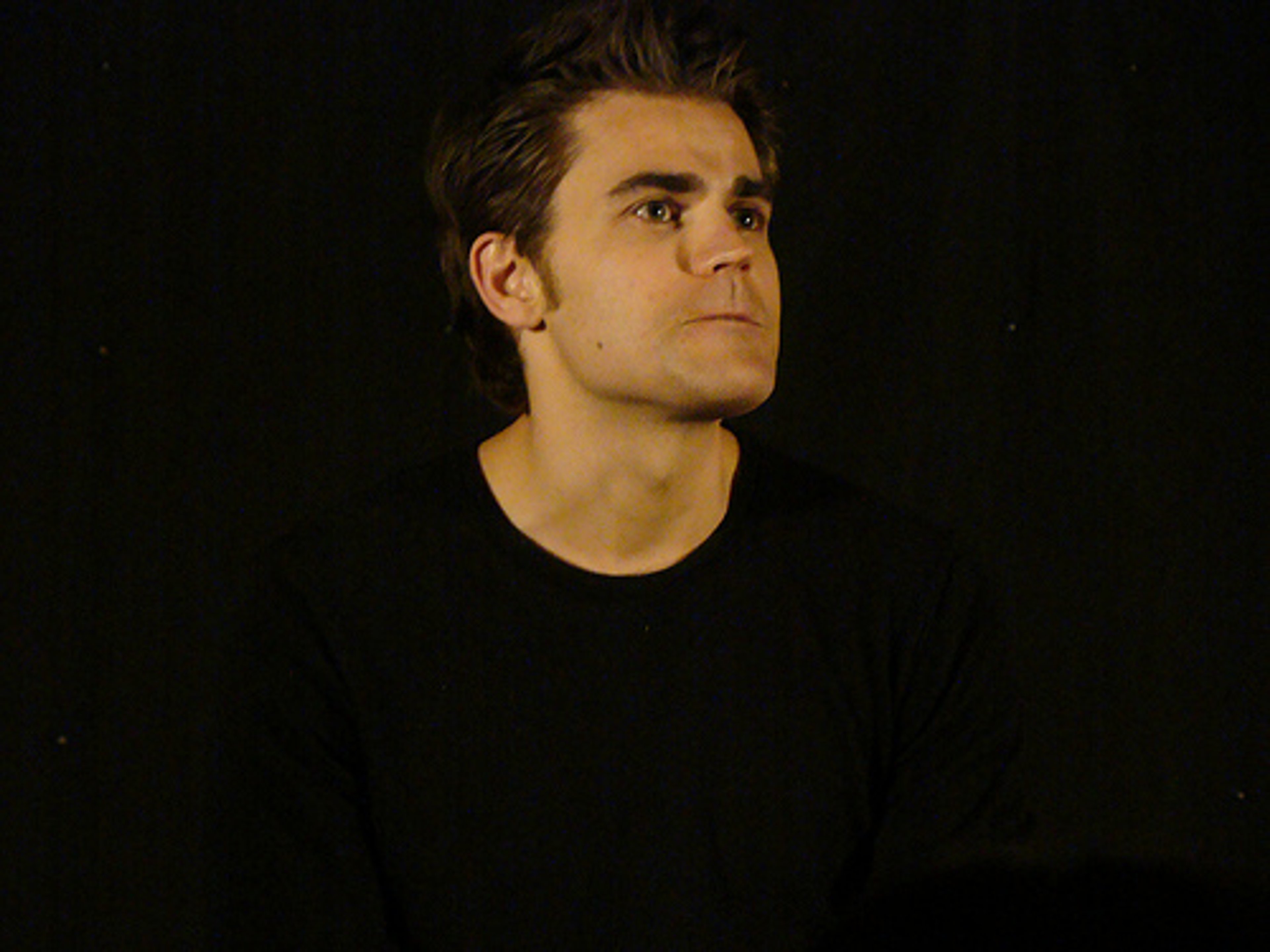 A young man with dark hair and a serious expression