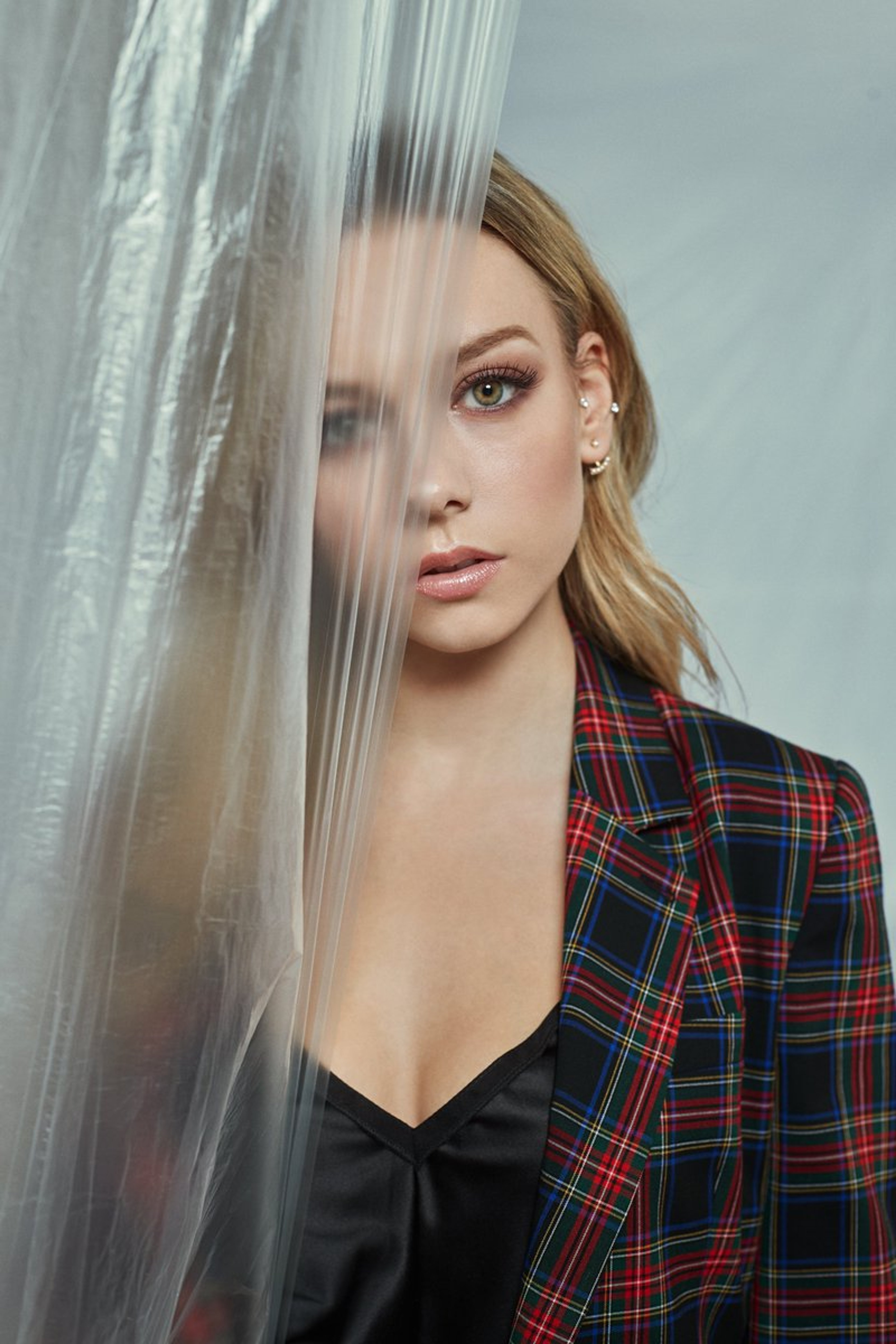 A young woman with blonde hair wearing a black top and plaid jacket