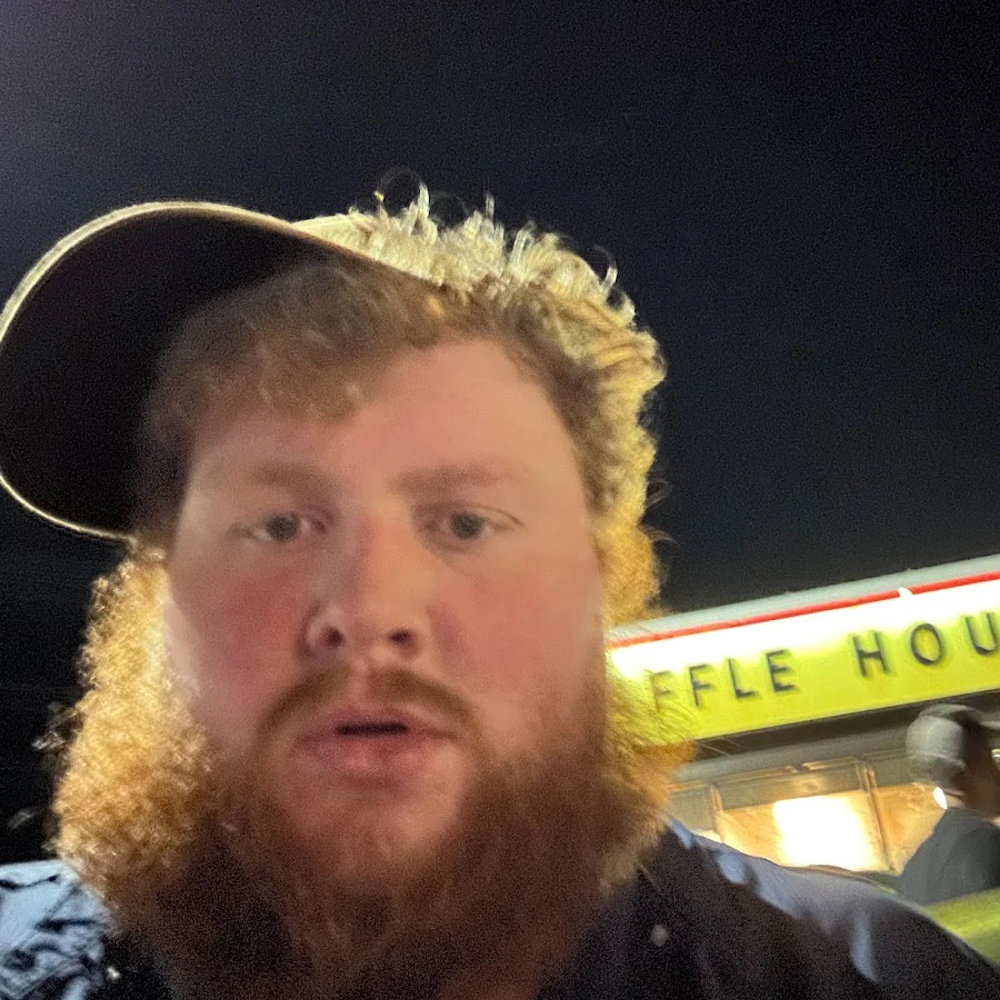 An obese man with a large beard wearing a baseball cap