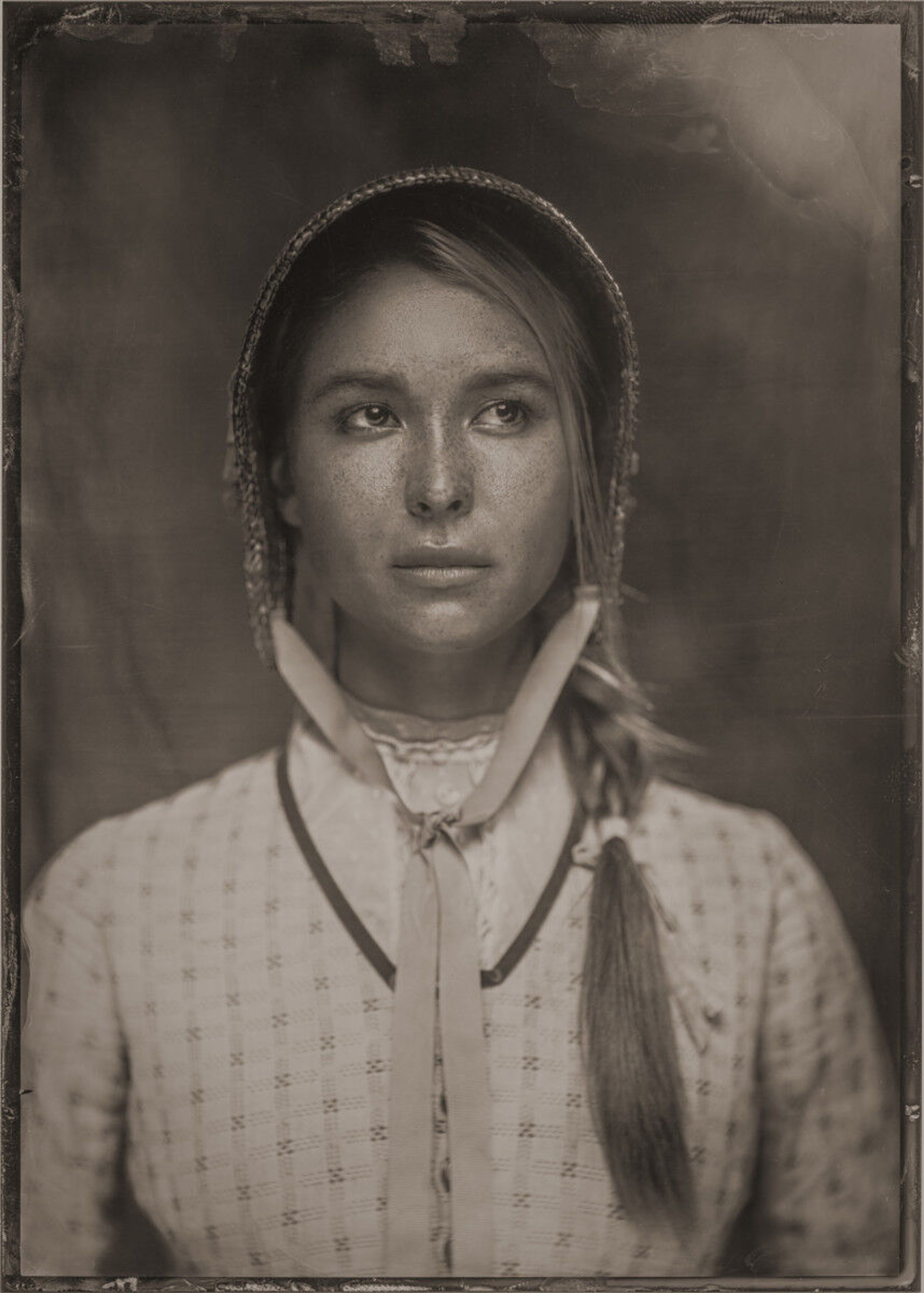 A young woman with dark hair wearing a white blouse, with a serious expression on her face.