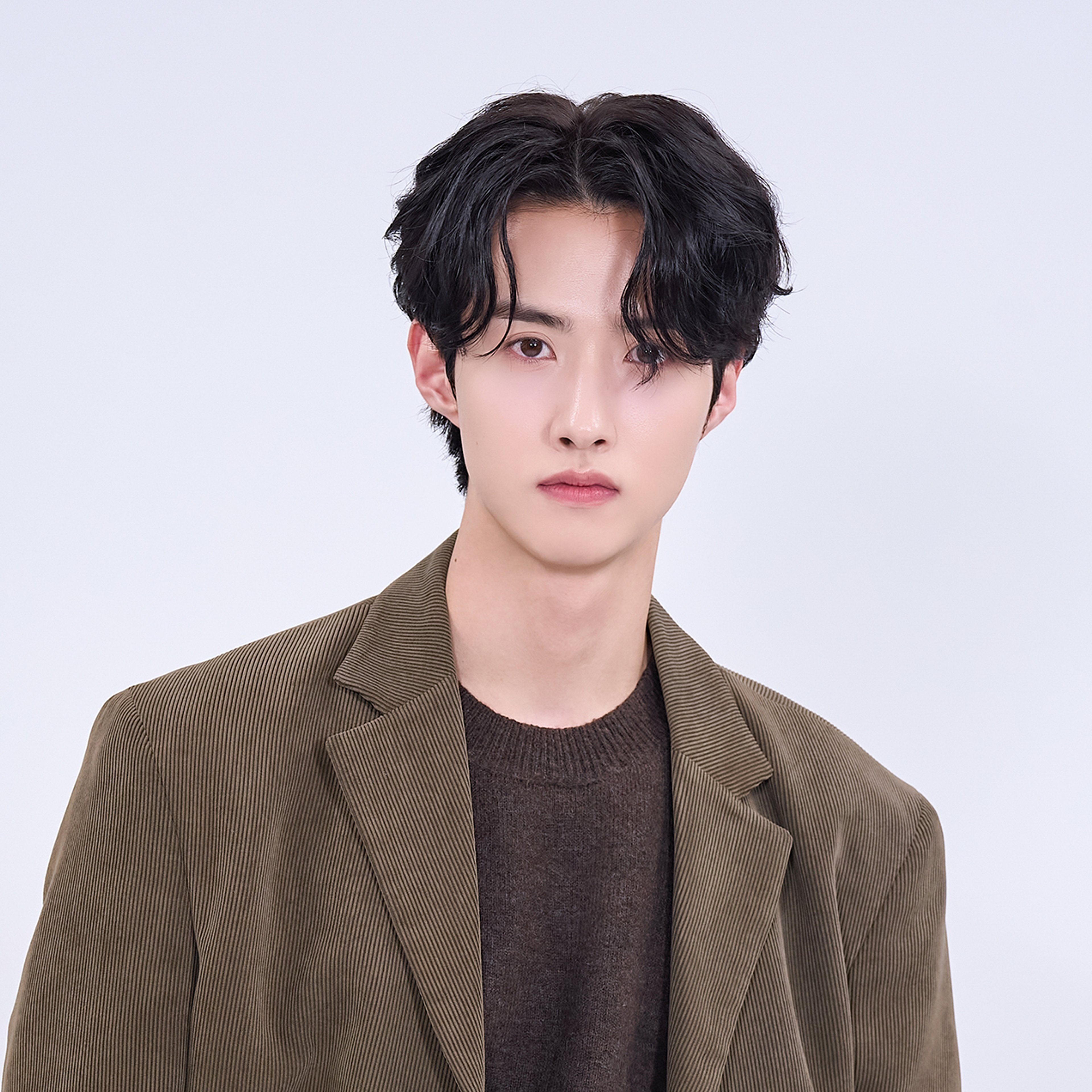 A young man with dark hair wearing a brown jacket