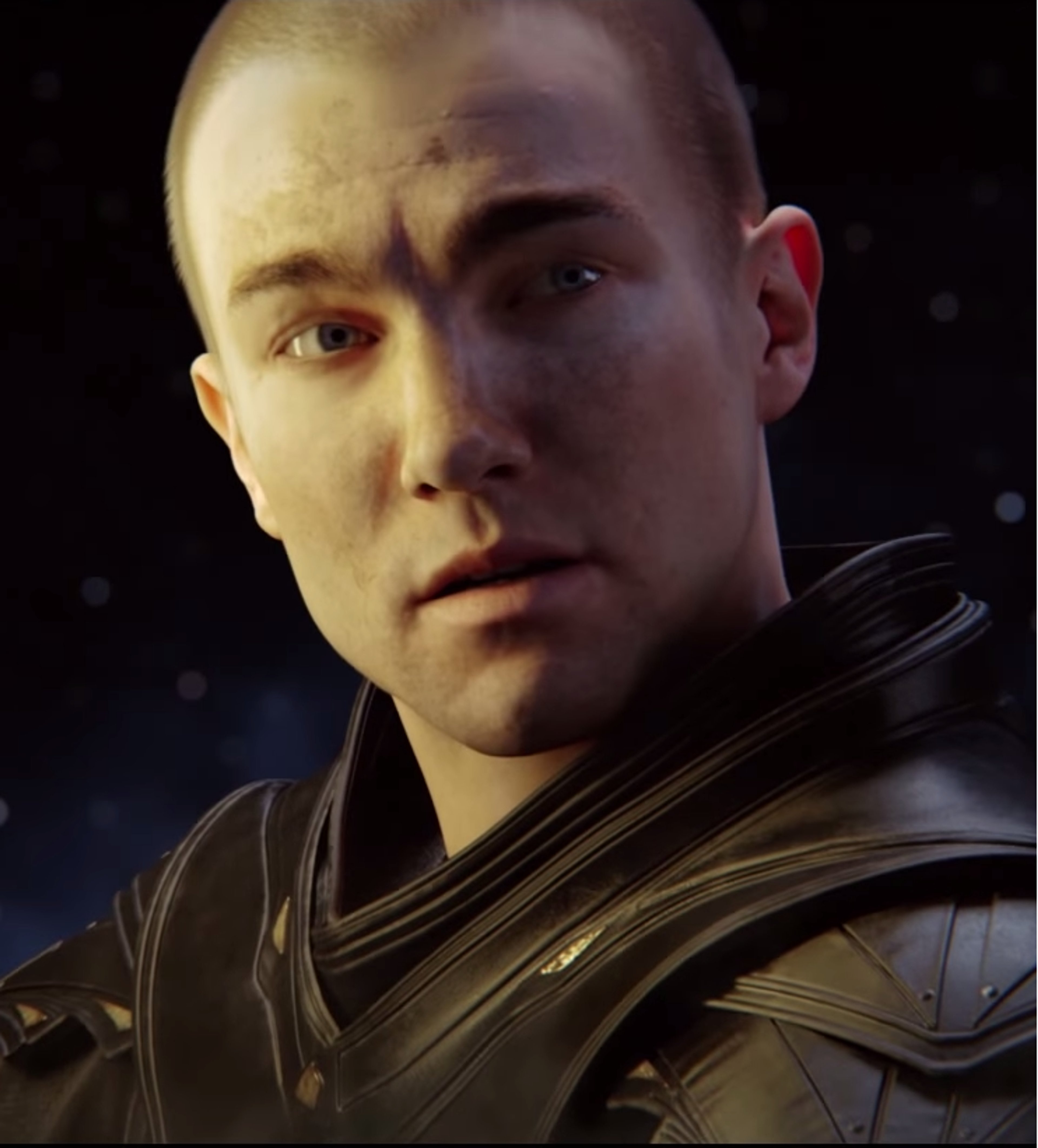 A young man with a shaved head wearing a dark outfit with a high collar, looking serious and intense.